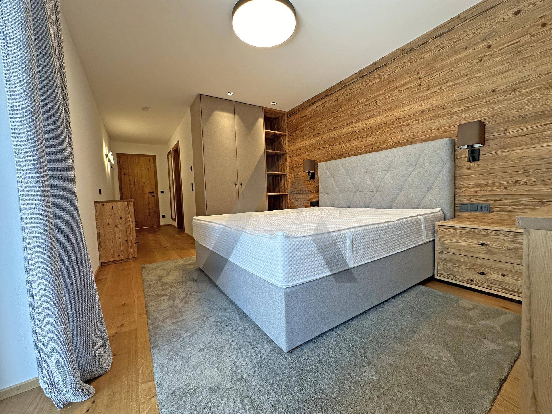 Helles Schlafzimmer mit Holzwänden, großem Bett und Einbauschränken.