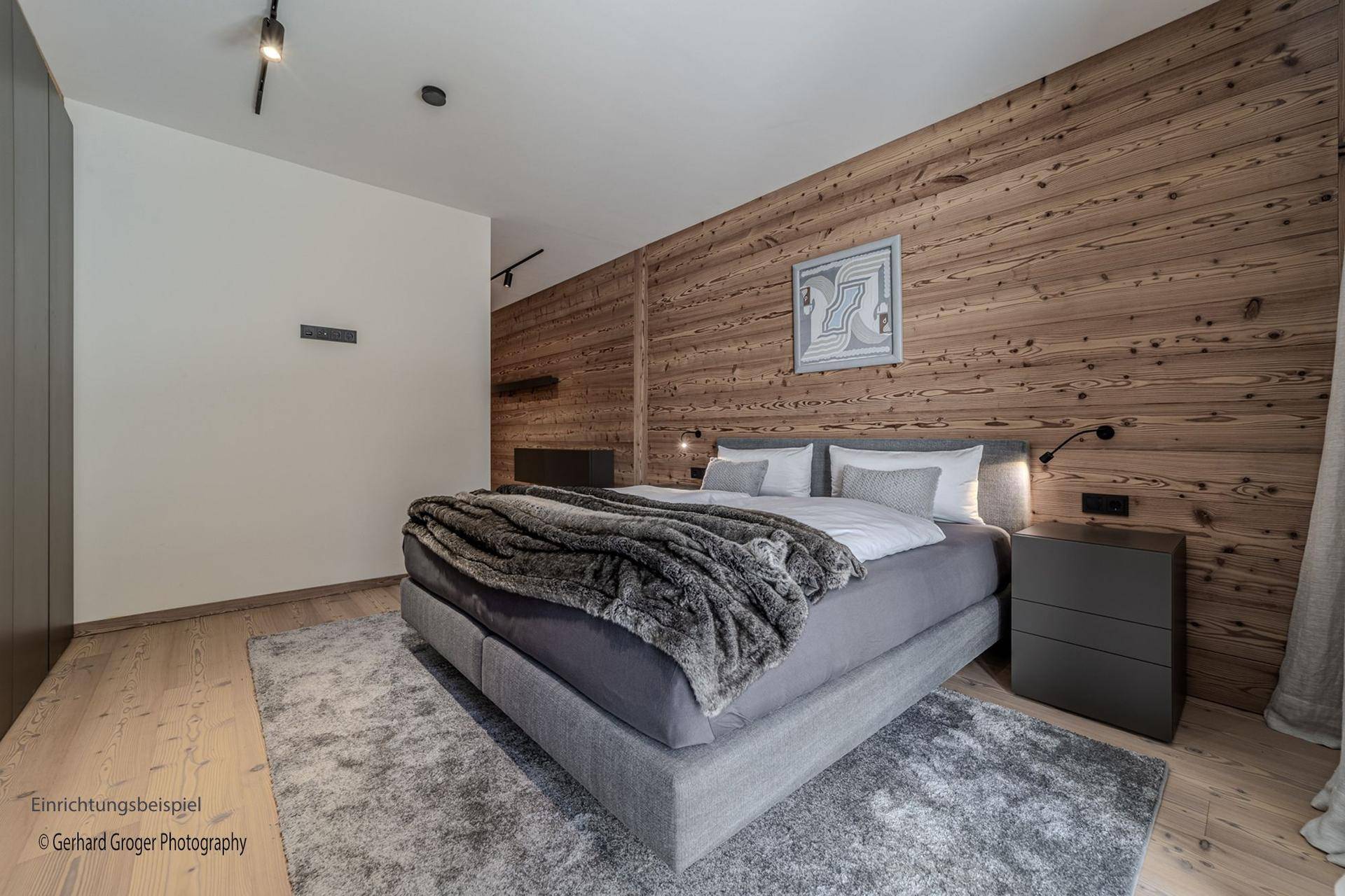 Modernes Schlafzimmer mit Holzwand, großem Doppelbett und weichem Teppichboden.
