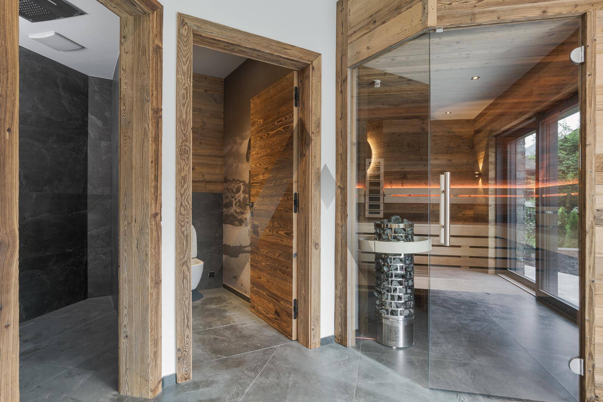 Exklusiver Wellnessbereich mit Sauna, Dusche und separatem WC in Holzoptik, modern gestaltet.