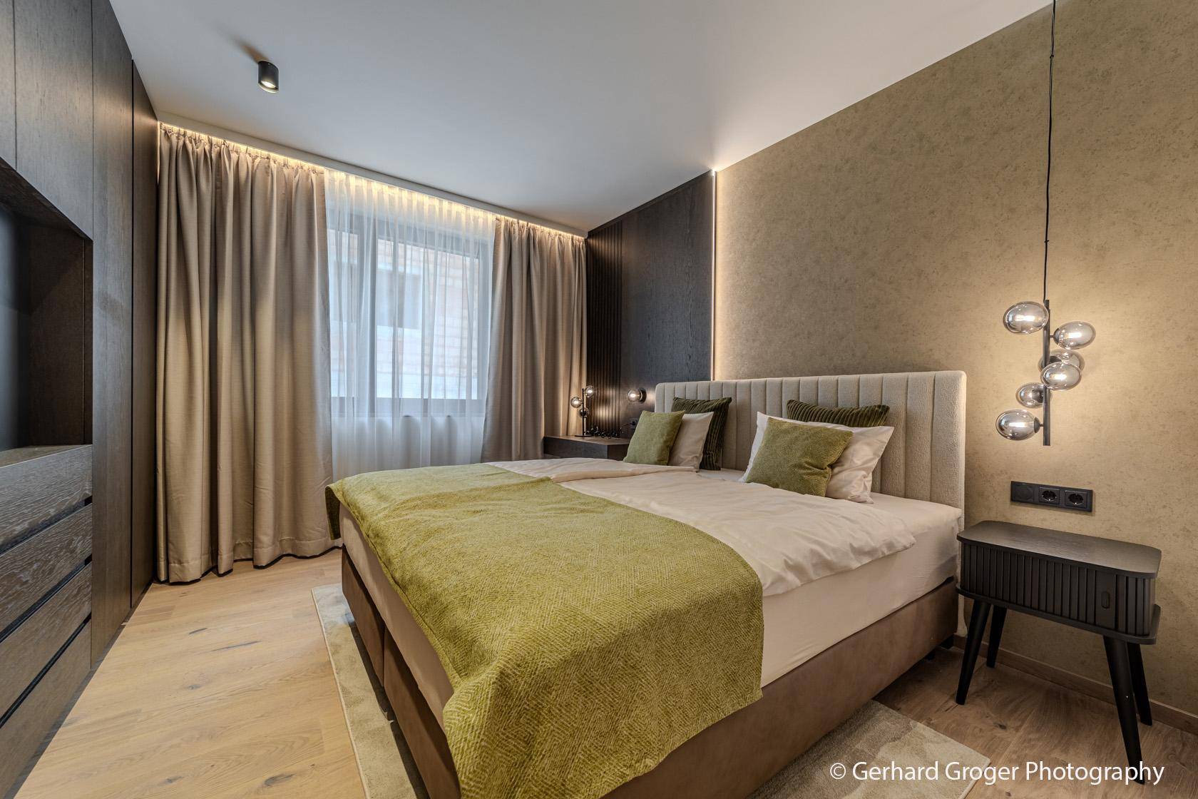 Helles Schlafzimmer mit großem Bett, Einbauschränken und Vorhängen für Privatsphäre.