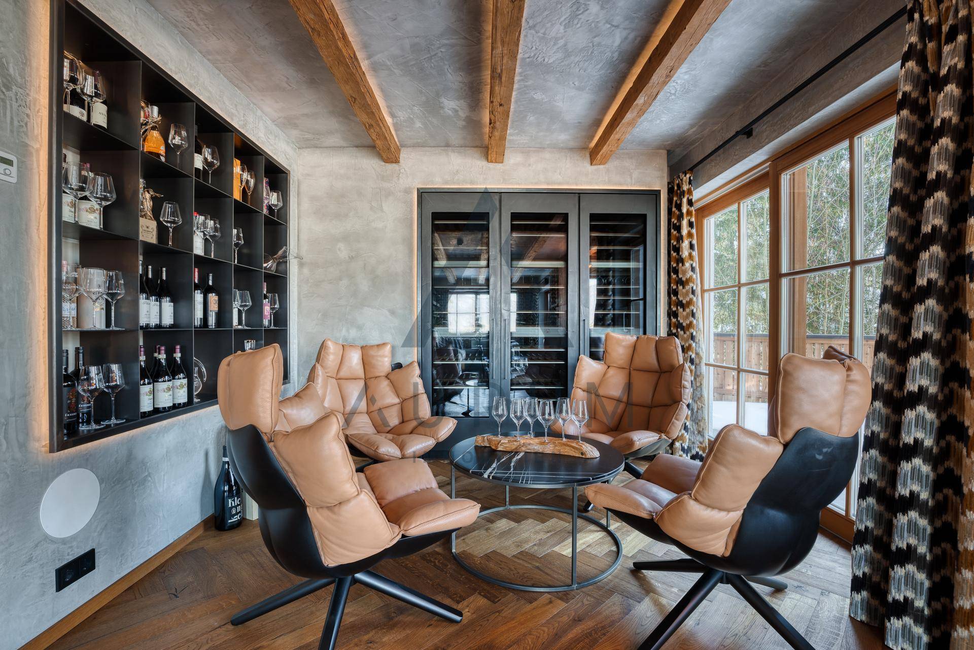 Gemütlicher Loungebereich mit Ledersesseln, Holzbalken und integriertem Weinkeller für gesellige Abende.