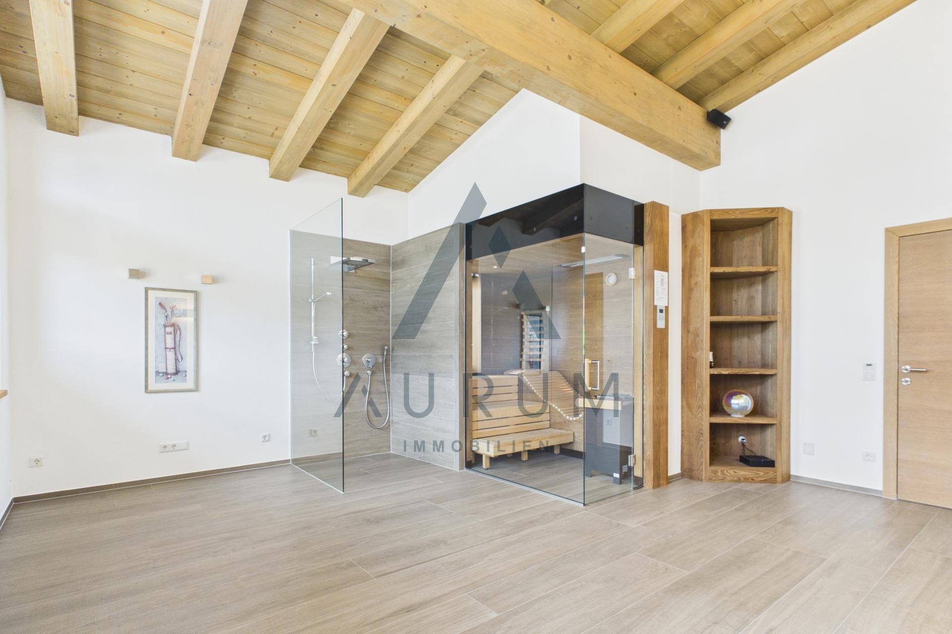 Moderner Wellnessbereich mit Sauna, Glasdusche und sichtbaren Holzdeckenbalken unter dem Dach.