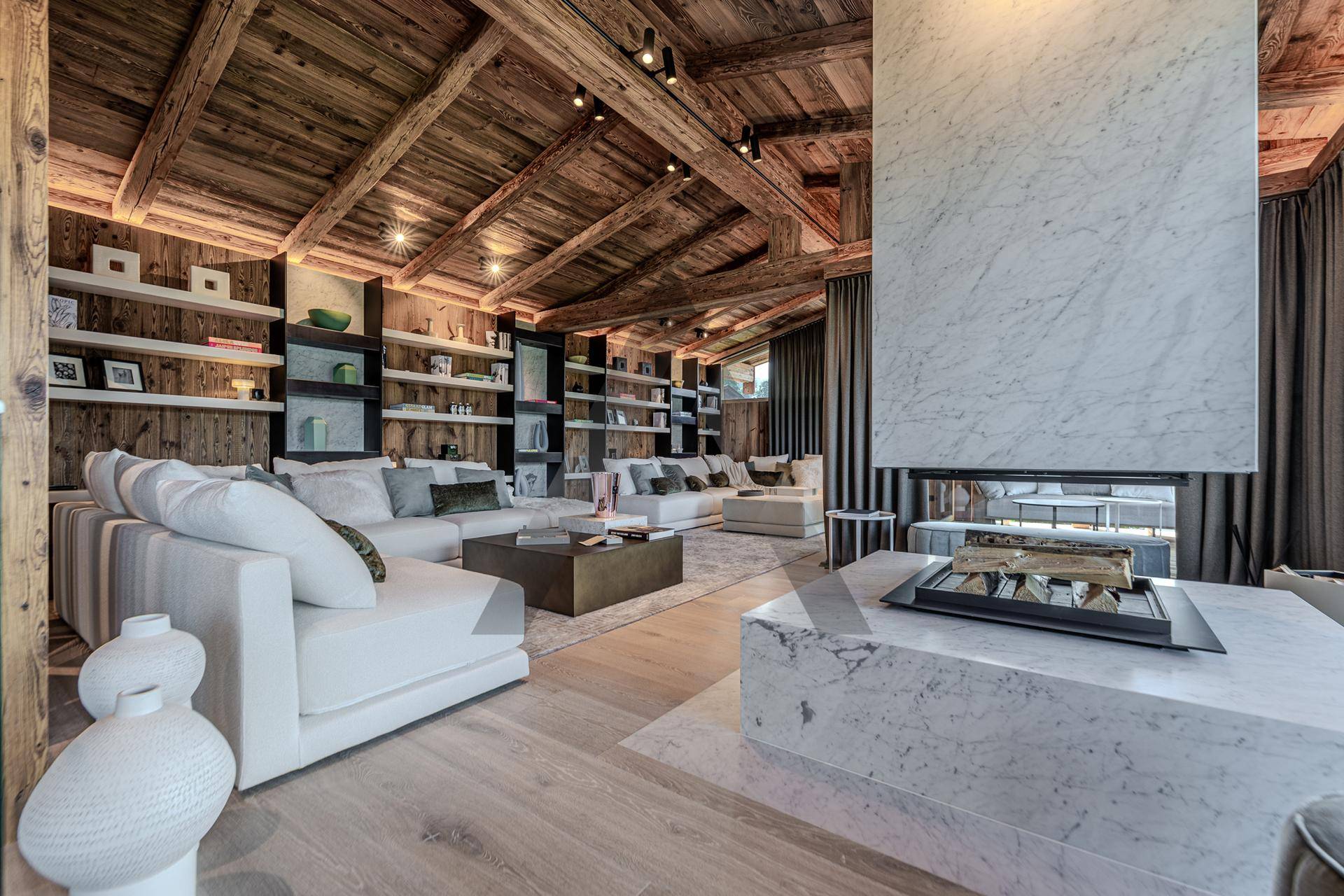 Luxuriöses Wohnzimmer mit Holzbalkendecke, Marmorkamin und bequemen weißen Sofas.