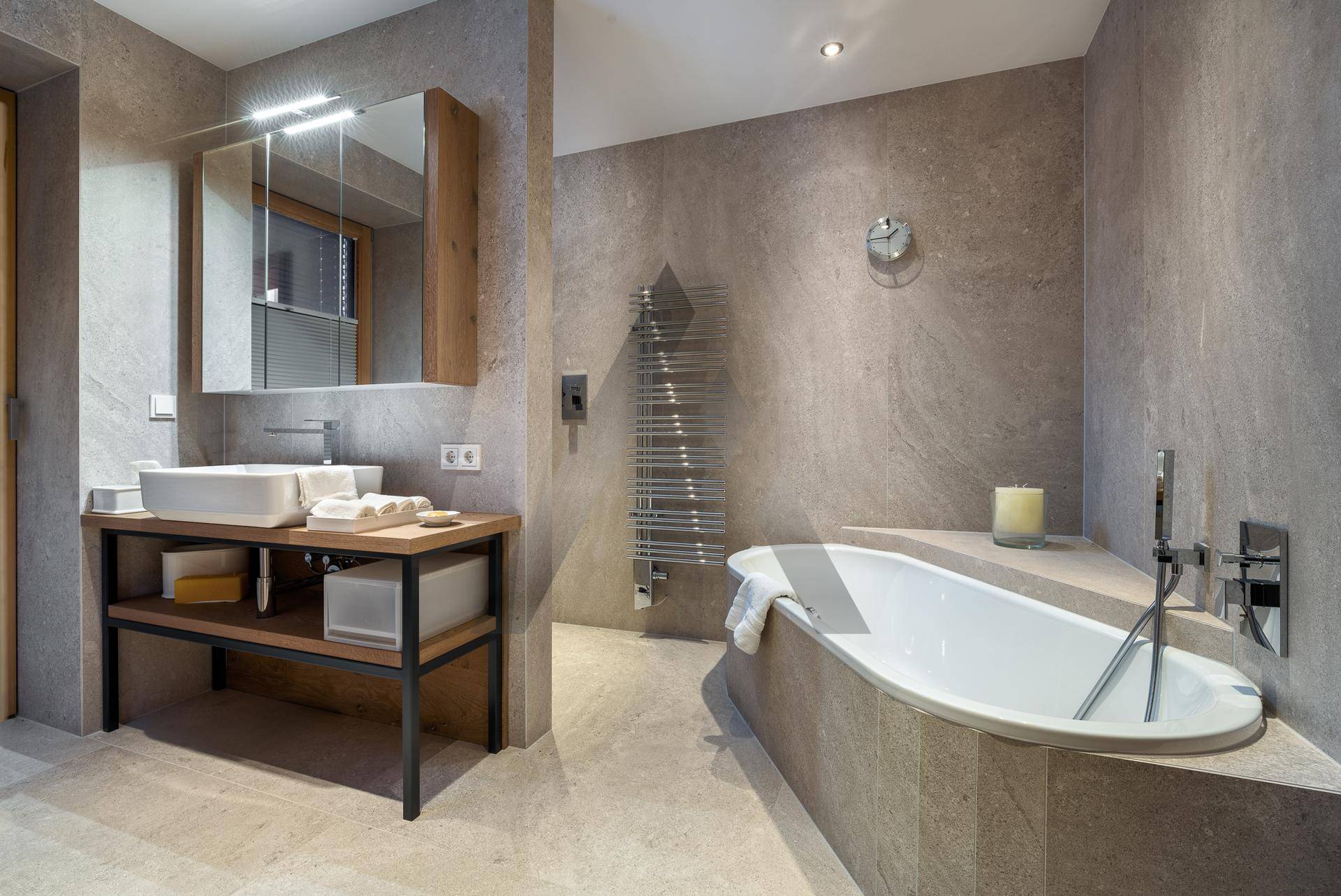 Elegantes Badezimmer mit Badewanne, modernem Waschtisch und beheiztem Handtuchhalter, in neutralen Farben.
