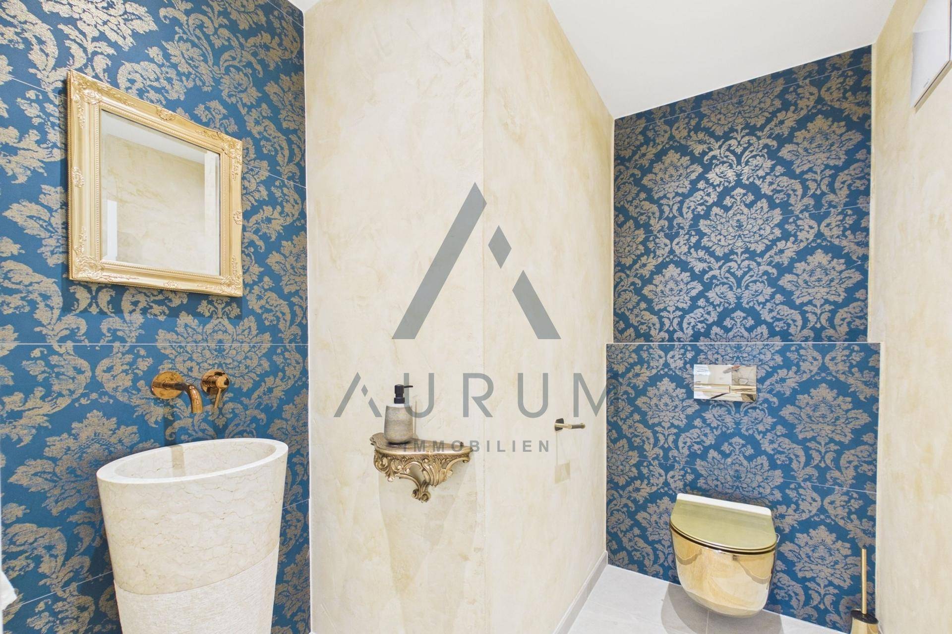 Elegantes Gäste-WC mit goldener Armatur, Standwaschbecken und gemusterter Tapete.