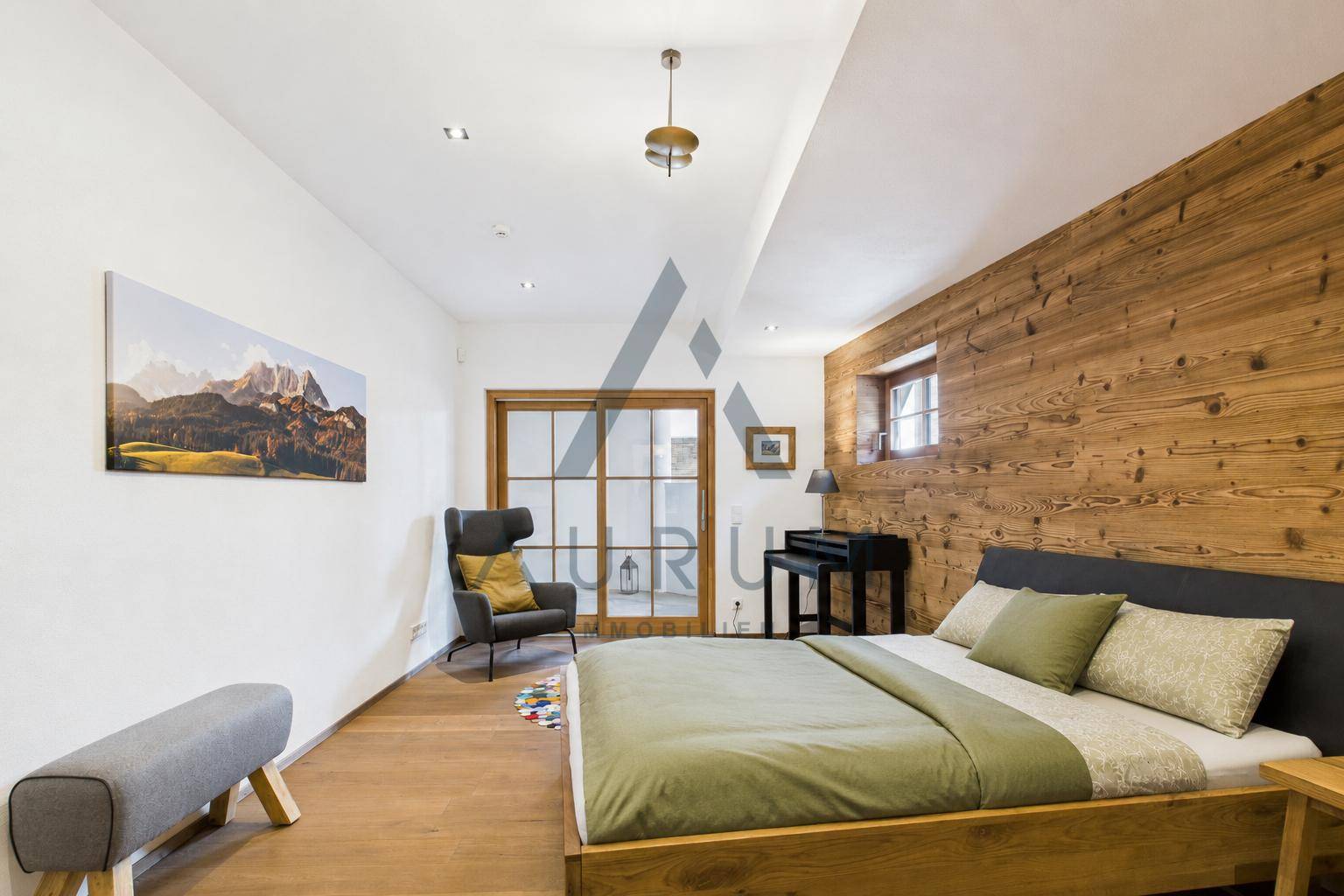 Geräumiges Schlafzimmer mit Holzwand, Holzboden und Zugang nach draußen.