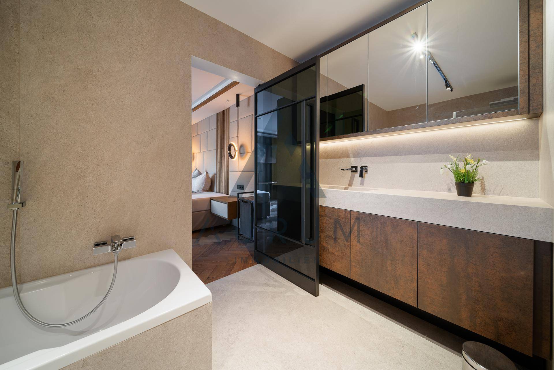 Modernes Badezimmer mit Badewanne, Einzelwaschbecken und direktem Zugang zum Schlafzimmer.