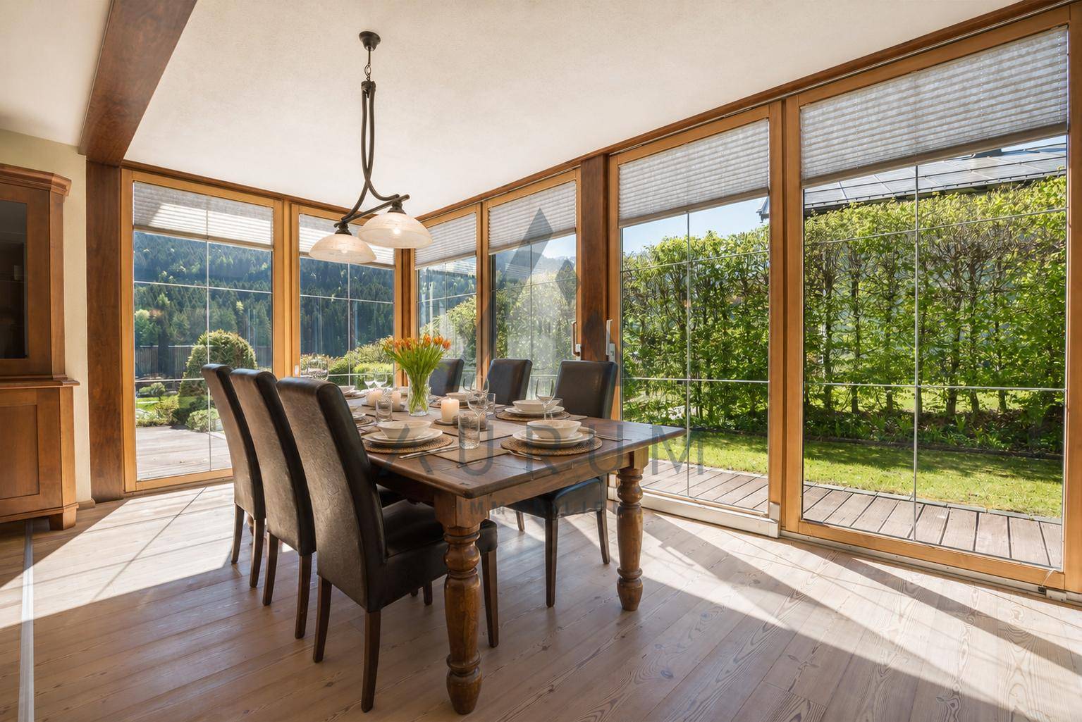 Heller Essbereich mit großem Holztisch, bequemen Stühlen und direktem Zugang zum Garten durch Panoramafenster.