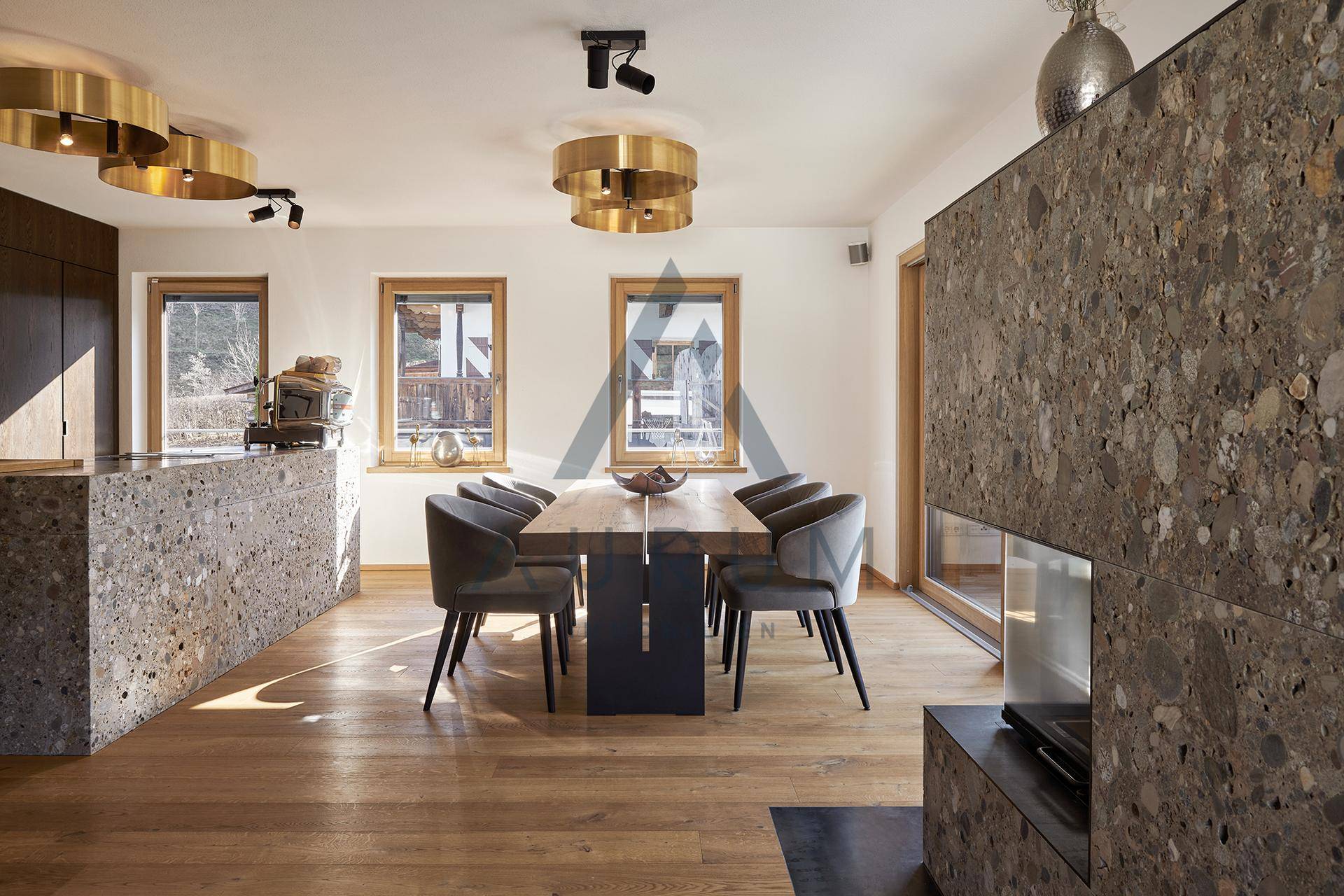 Heller Essbereich mit Holztisch, modernen Leuchten und Steinwand mit Kamin.