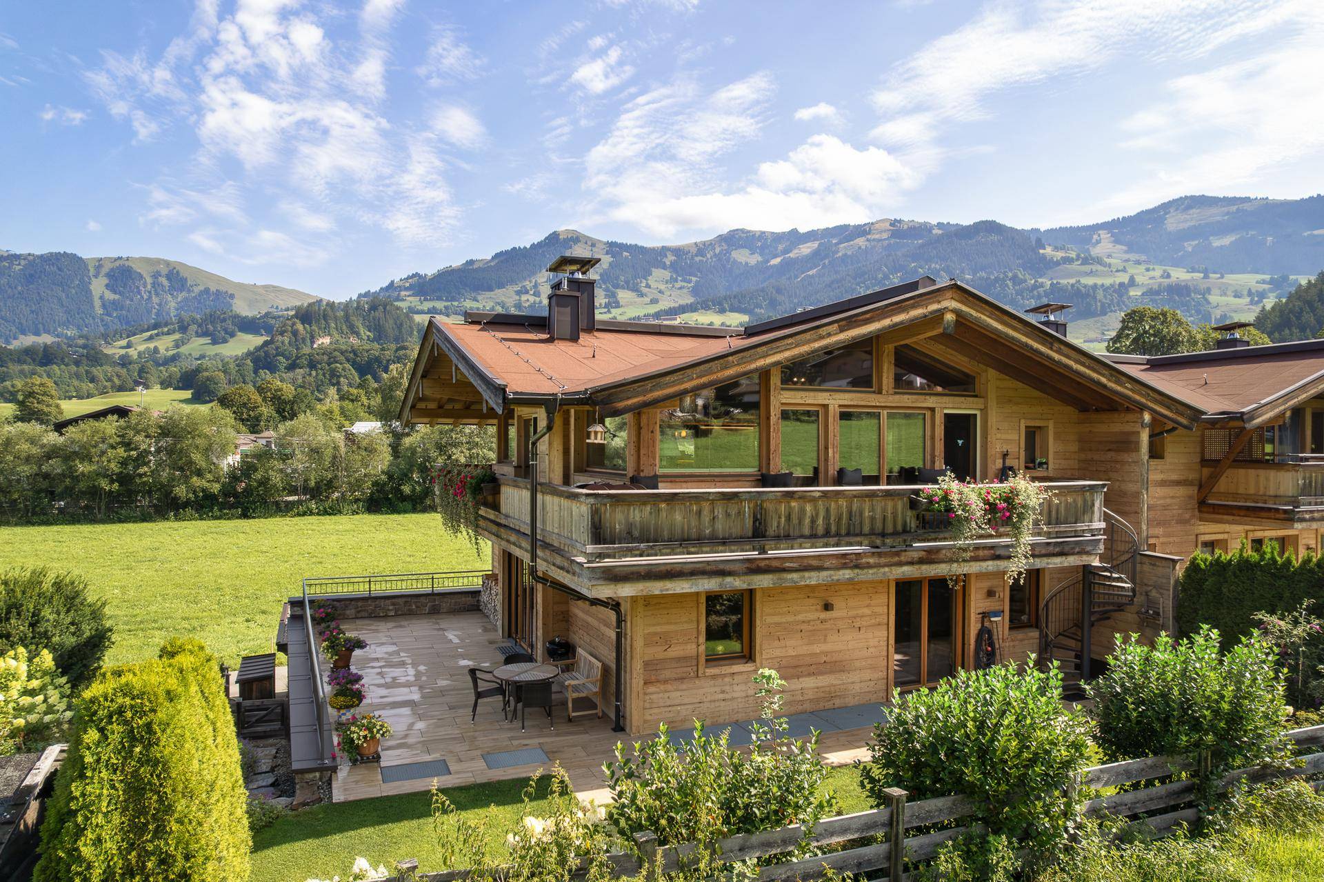 Charmantes Holzhaus im alpinen Stil mit Balkonen, Terrasse und umgebender Natur.