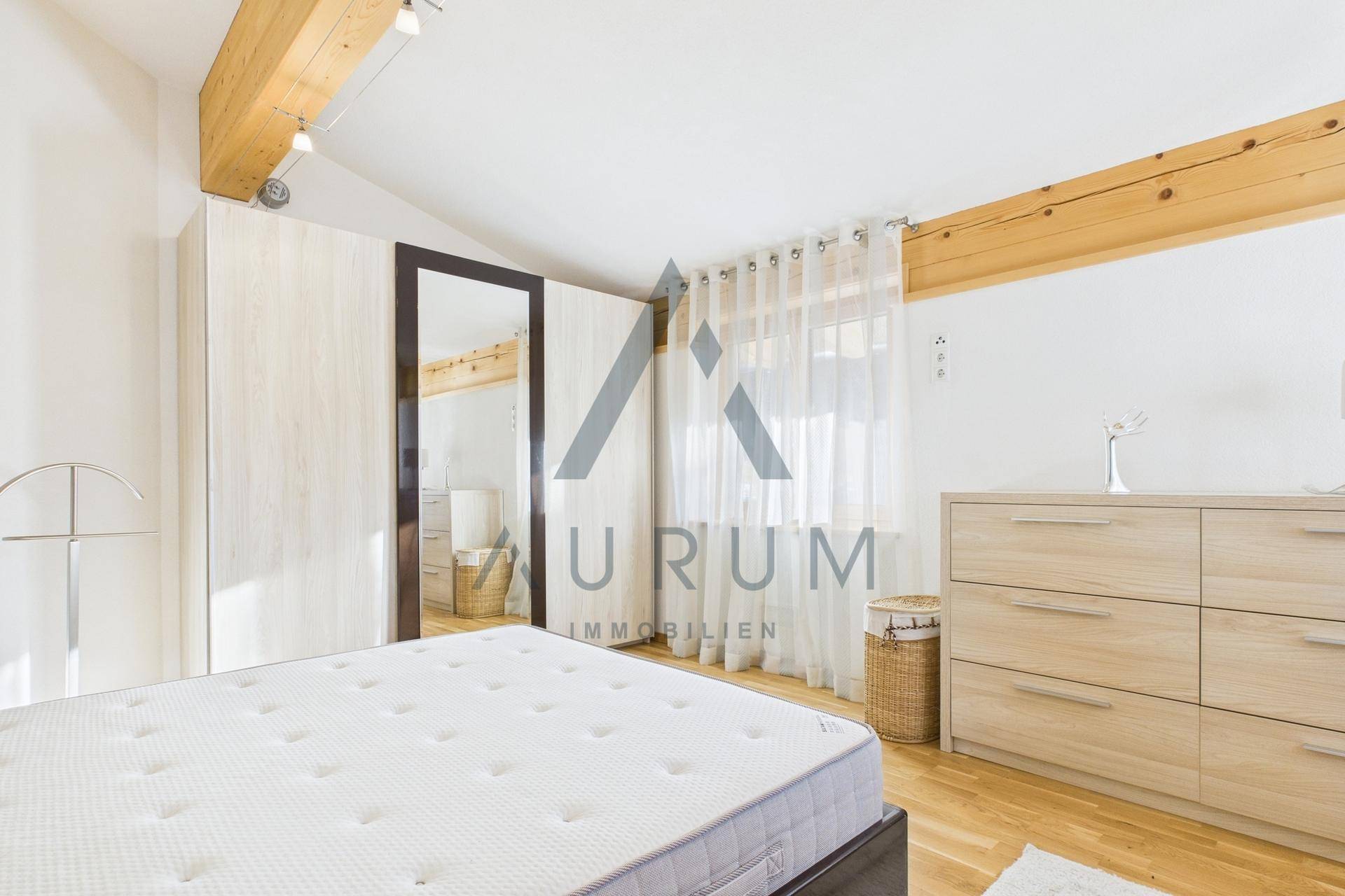 Geräumiges Schlafzimmer mit Holzboden, großem Kleiderschrank und sichtbaren Holzbalken an der Decke.