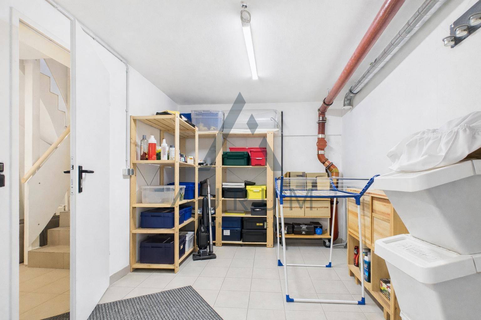 Geräumiger Abstellraum mit Regalen für diverse Haushaltsgegenstände und Zugang zur Treppe.