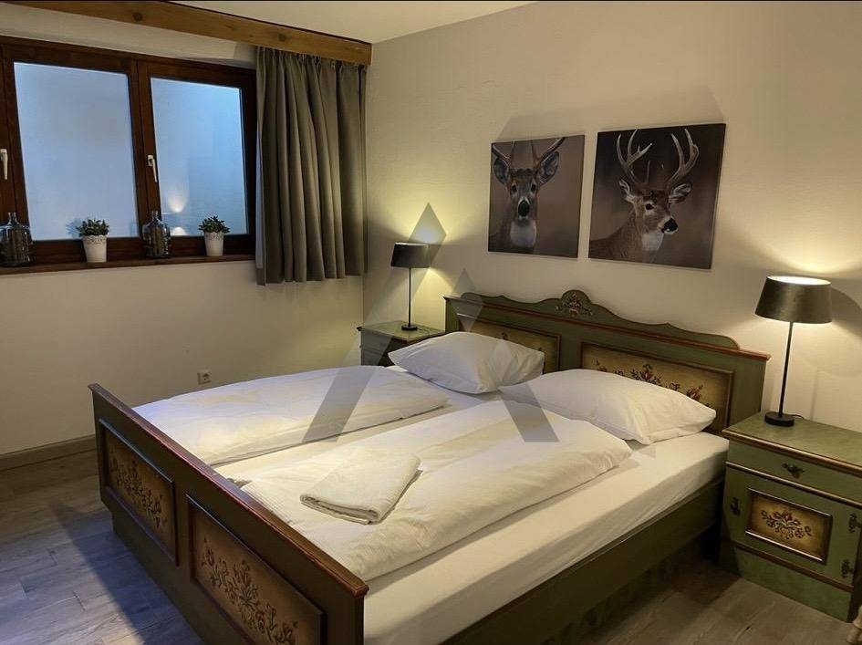 Rustikales Schlafzimmer mit bemaltem Holzdoppelbett und Hirschmotiven an der Wand.