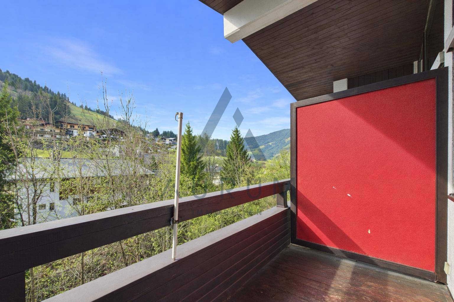 Geräumiger Balkon mit Holzboden und weitem Blick auf die bewaldeten Berghänge.