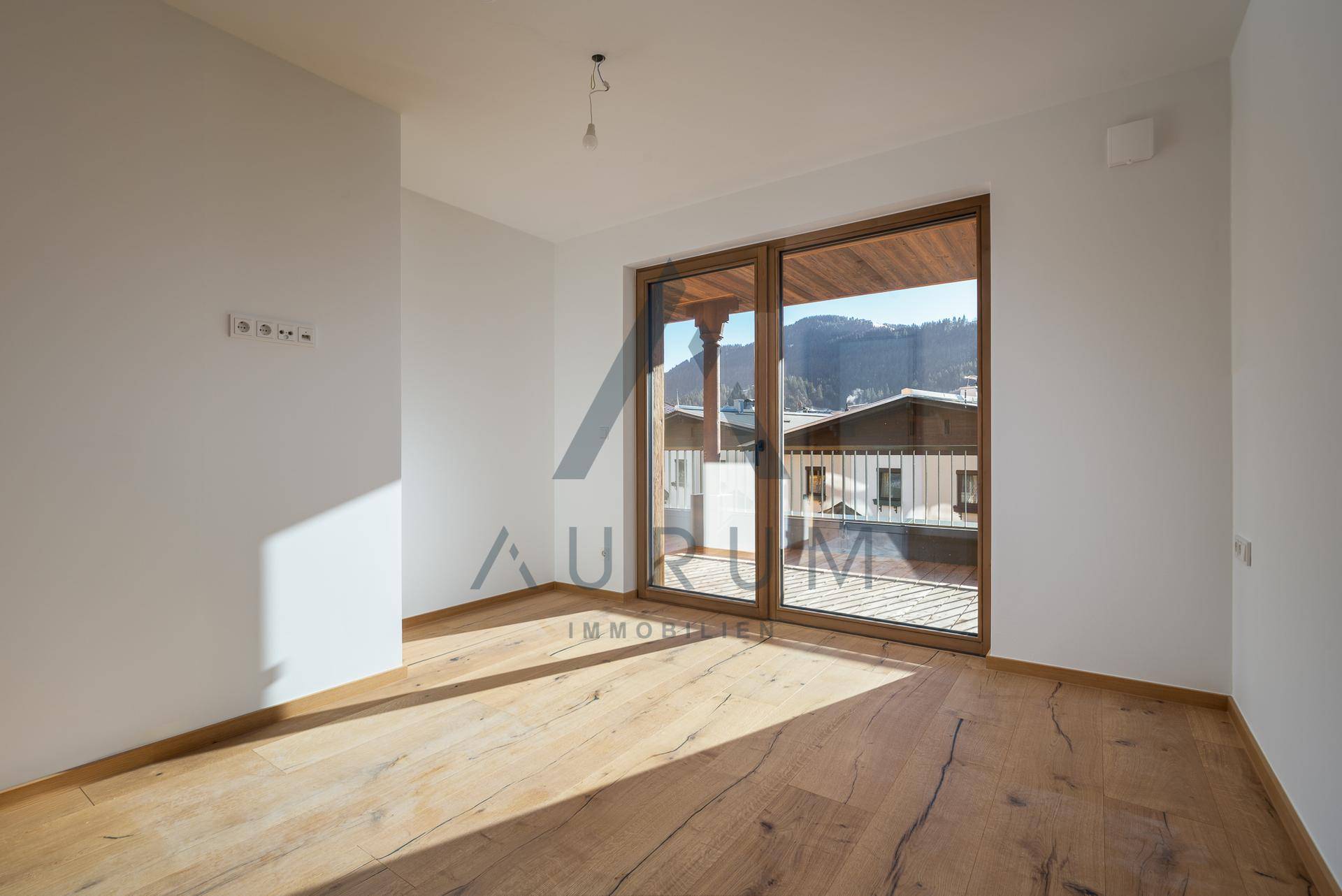 Geräumiges Schlafzimmer mit Holzboden und großem Fenster mit Zugang zu einem Balkon.