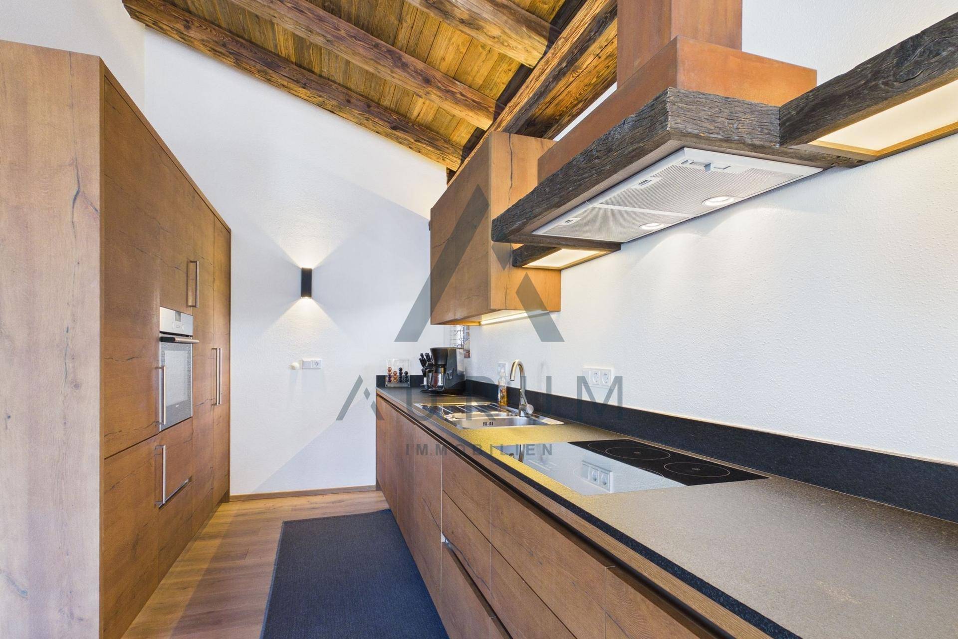 Moderne Einbauküche mit Holzfronten, dunkler Arbeitsplatte und integrierten Geräten.