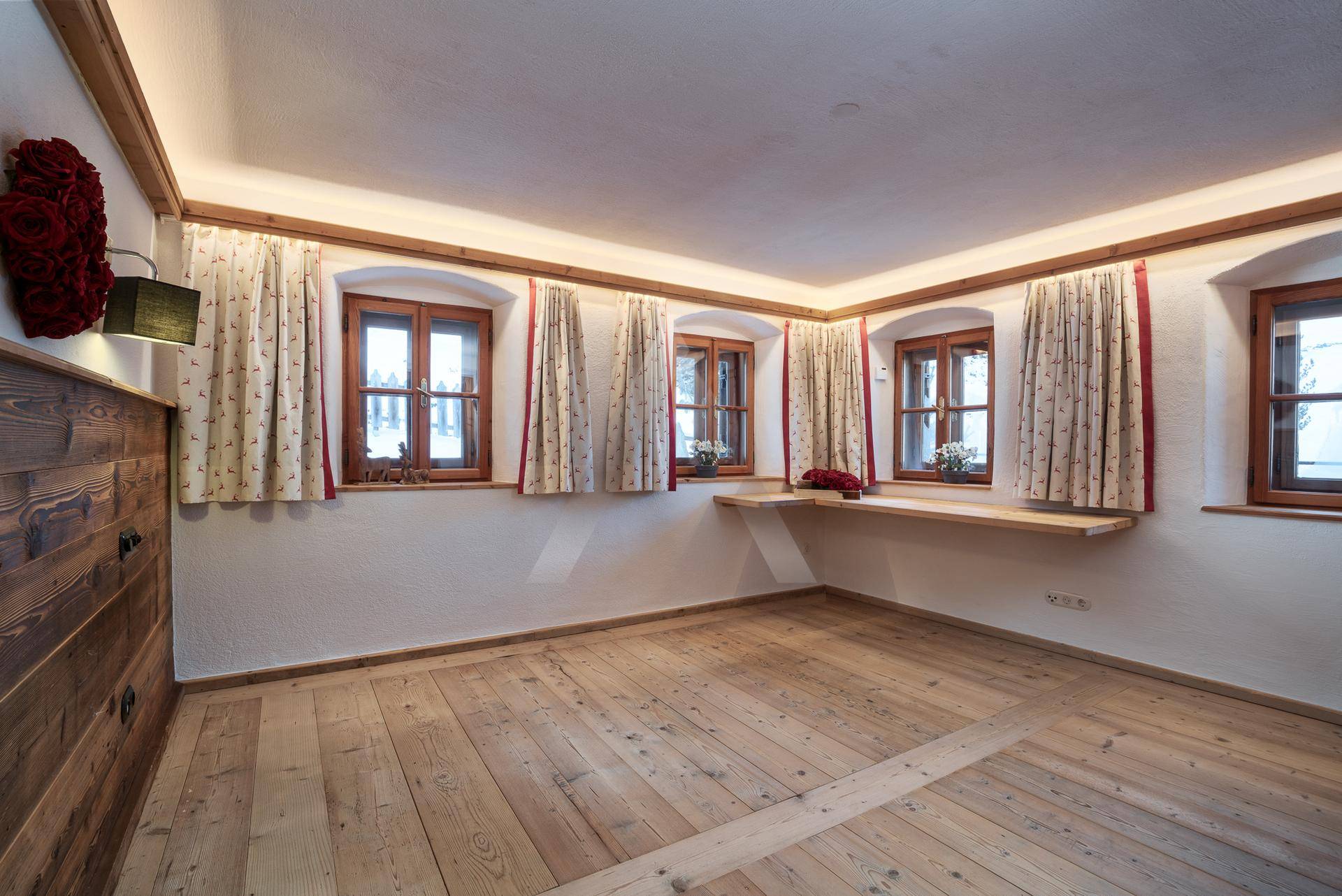 Geräumiges Zimmer mit Holzboden, Holzelementen und mehreren Fenstern.