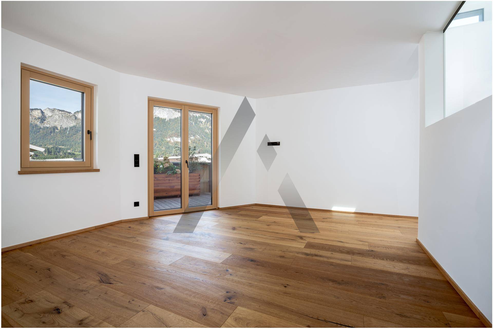 Heller Wohnraum mit Holzboden und großen Fenstern, die einen schönen Bergblick bieten.
