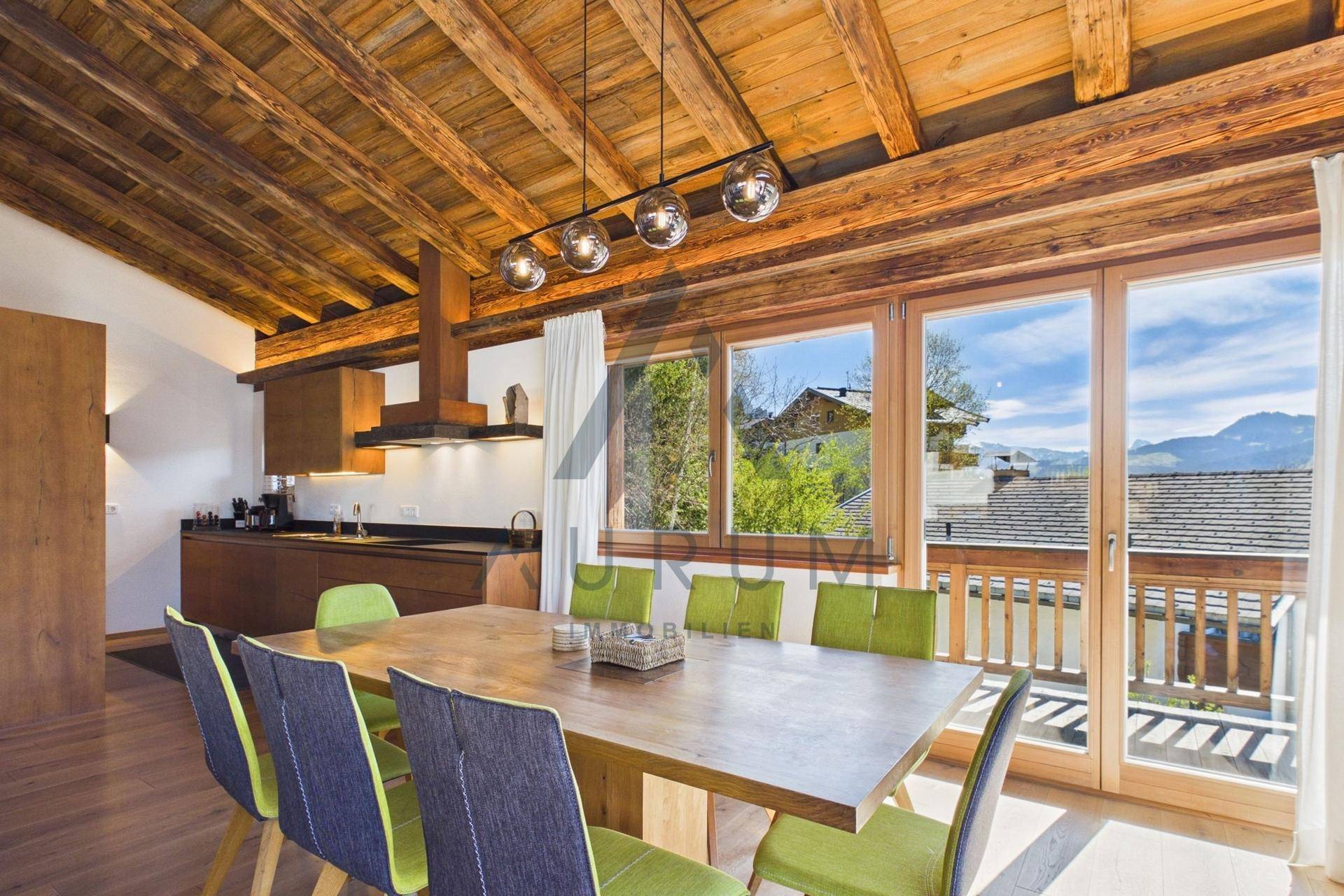 Heller Essbereich mit Holztisch, modernen Stühlen und Zugang zum Balkon mit Bergblick.
