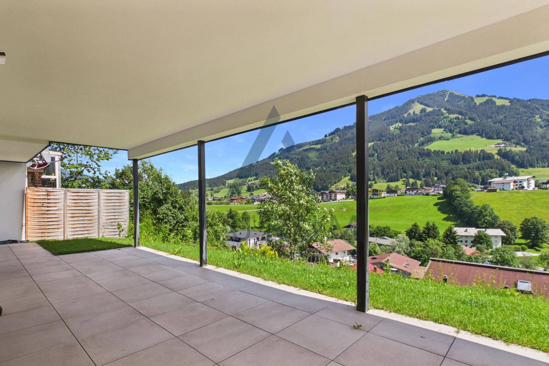Große, geflieste Terrasse im Erdgeschoss mit weitem Blick auf die grüne Landschaft.
