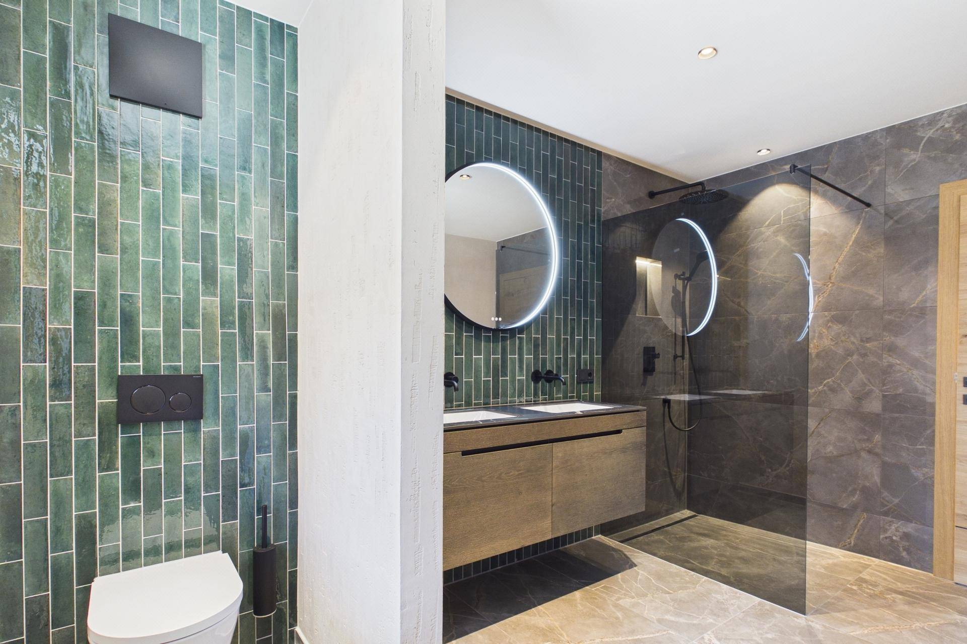 Modernes Badezimmer mit Doppelwaschbecken, begehbarer Dusche und grünen Fliesen.