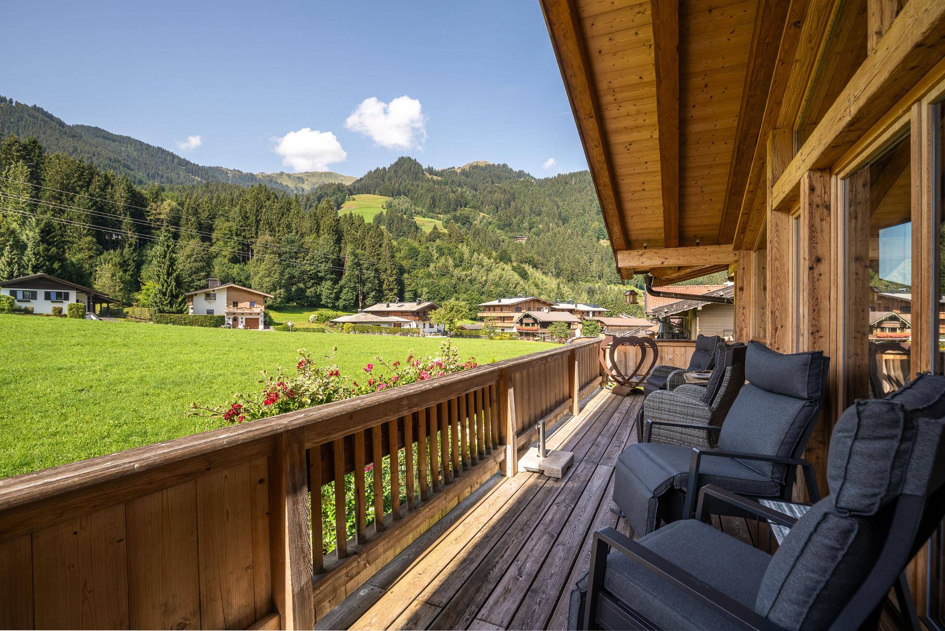 Geräumiger Holzbalkon mit bequemen Sitzgelegenheiten und weitem Blick auf die umliegende Natur.