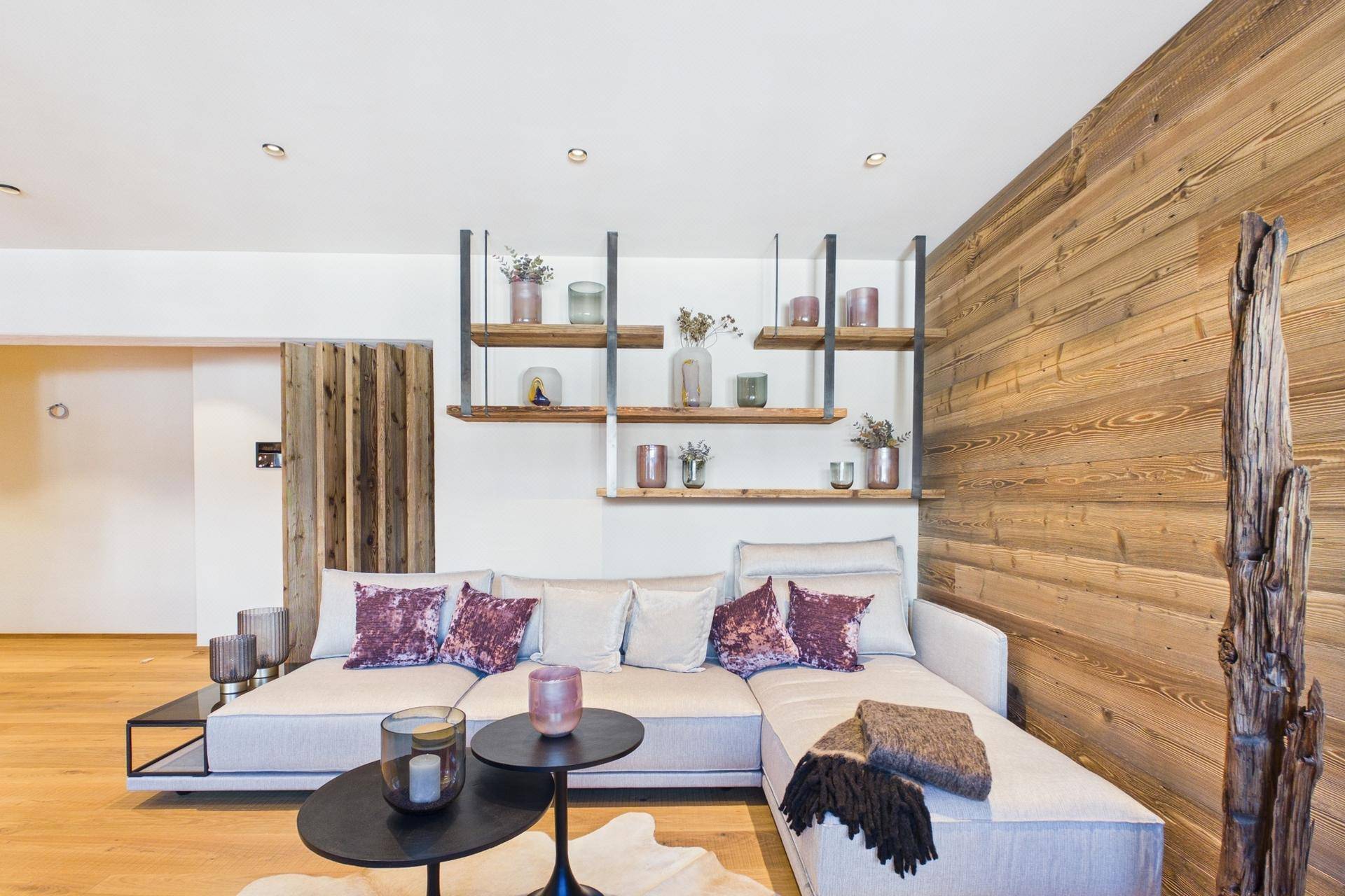 Modernes Wohnzimmer mit Holzwand, bequemer Couch und dekorativen Regalen.