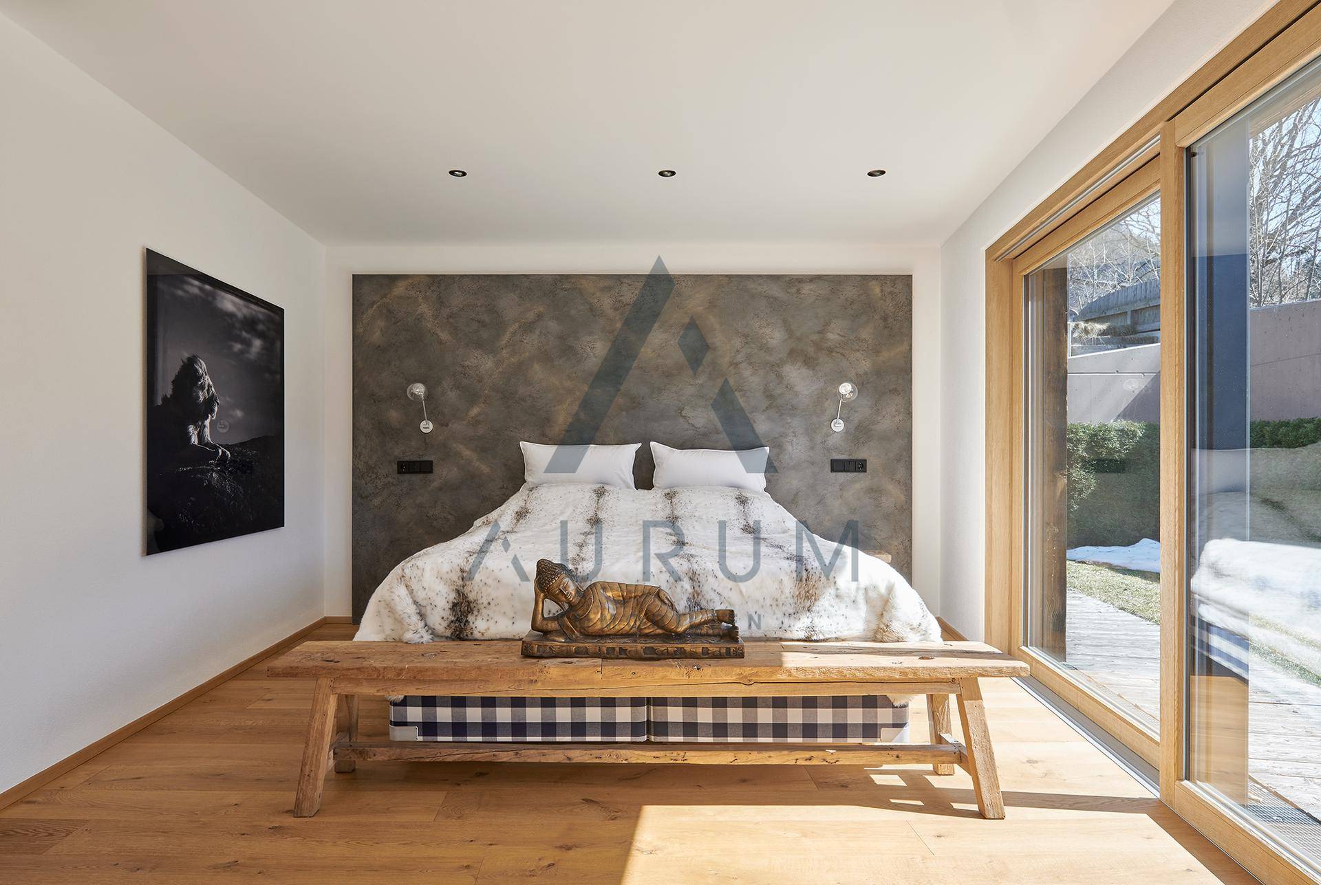 Schlafzimmer mit Holzboden, großer Fensterfront und Zugang zum Garten.