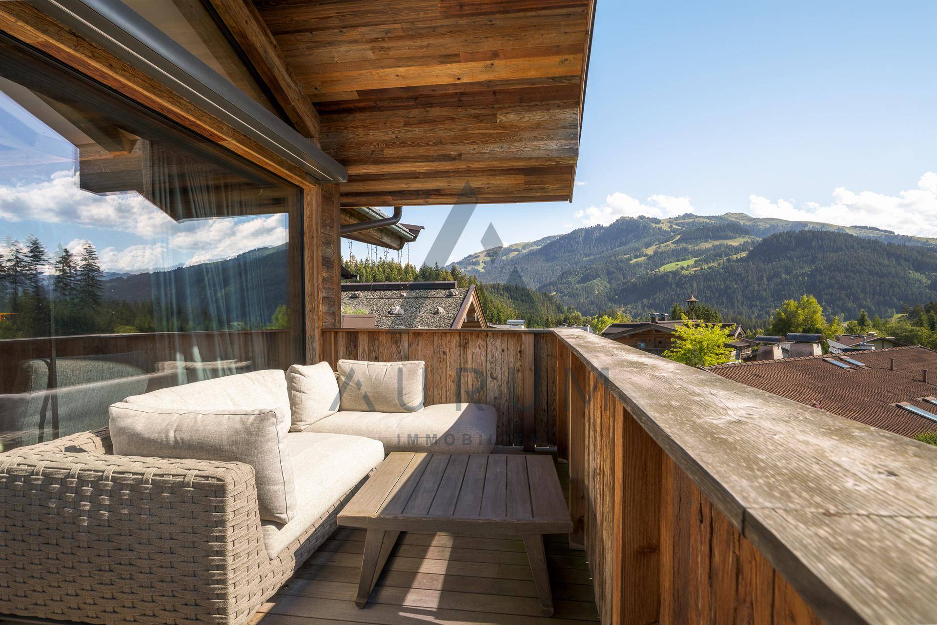 Gemütlicher Holzbalkon mit Sitzgelegenheiten und weitem Blick auf die umliegende Bergwelt.