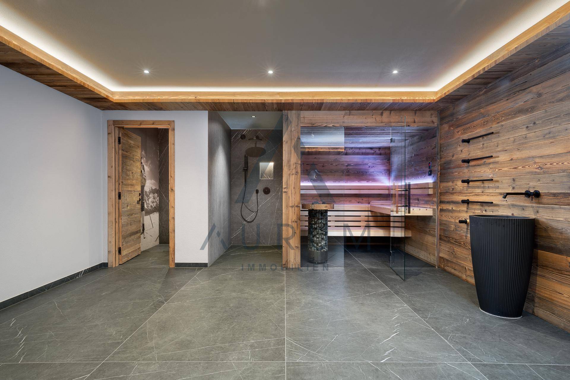 Moderner Wellnessbereich mit Sauna, großer Dusche und stilvollen Fliesen.