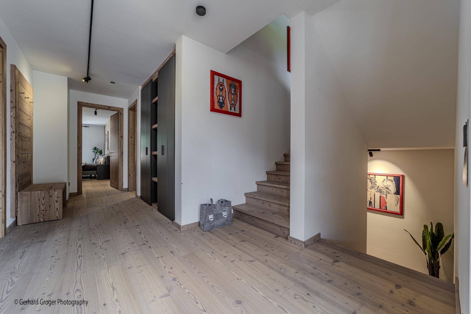 Heller Flur mit Holztreppe, Holzboden und moderner Dekoration.