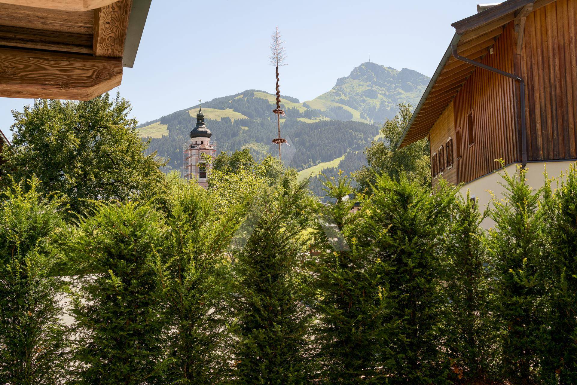 Malerischer Ausblick auf bewaldete Berge und eine Kirche im Tal.