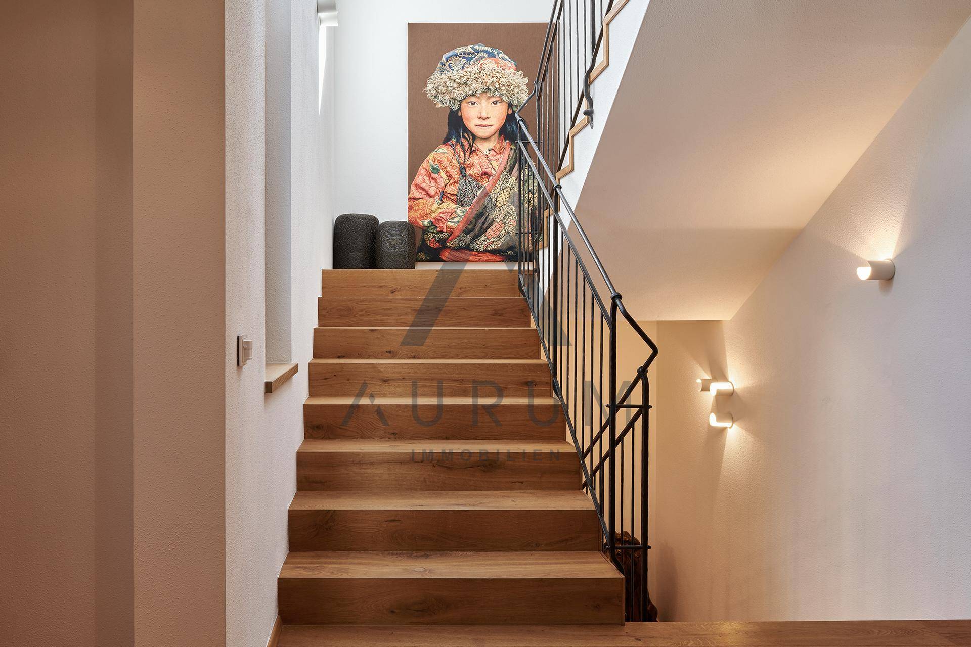 Heller Treppenaufgang mit Holzstufen und modernem Geländer, geschmückt mit Kunst.