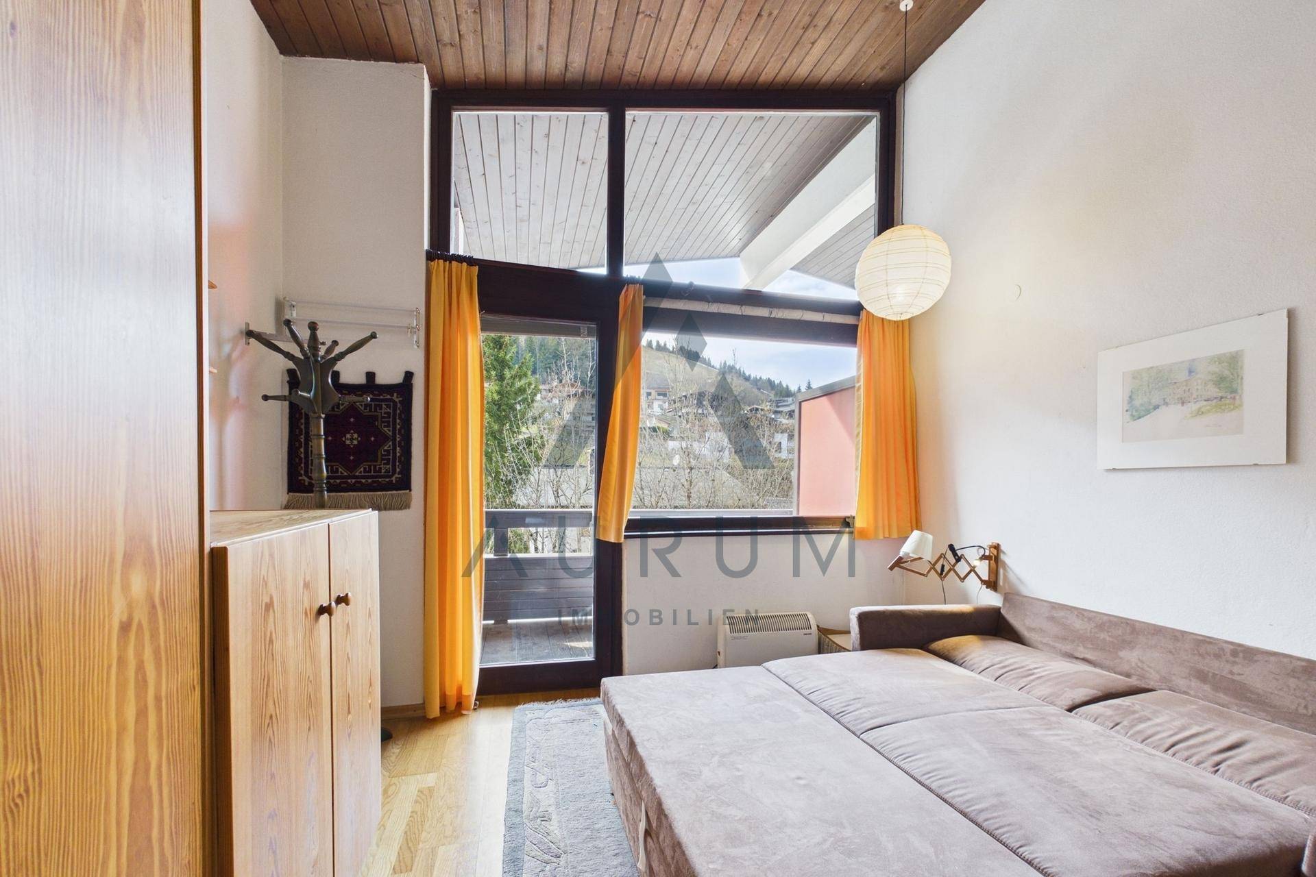 Schlafzimmer mit Zugang zum Balkon, großen Fenstern und Blick auf die Natur.