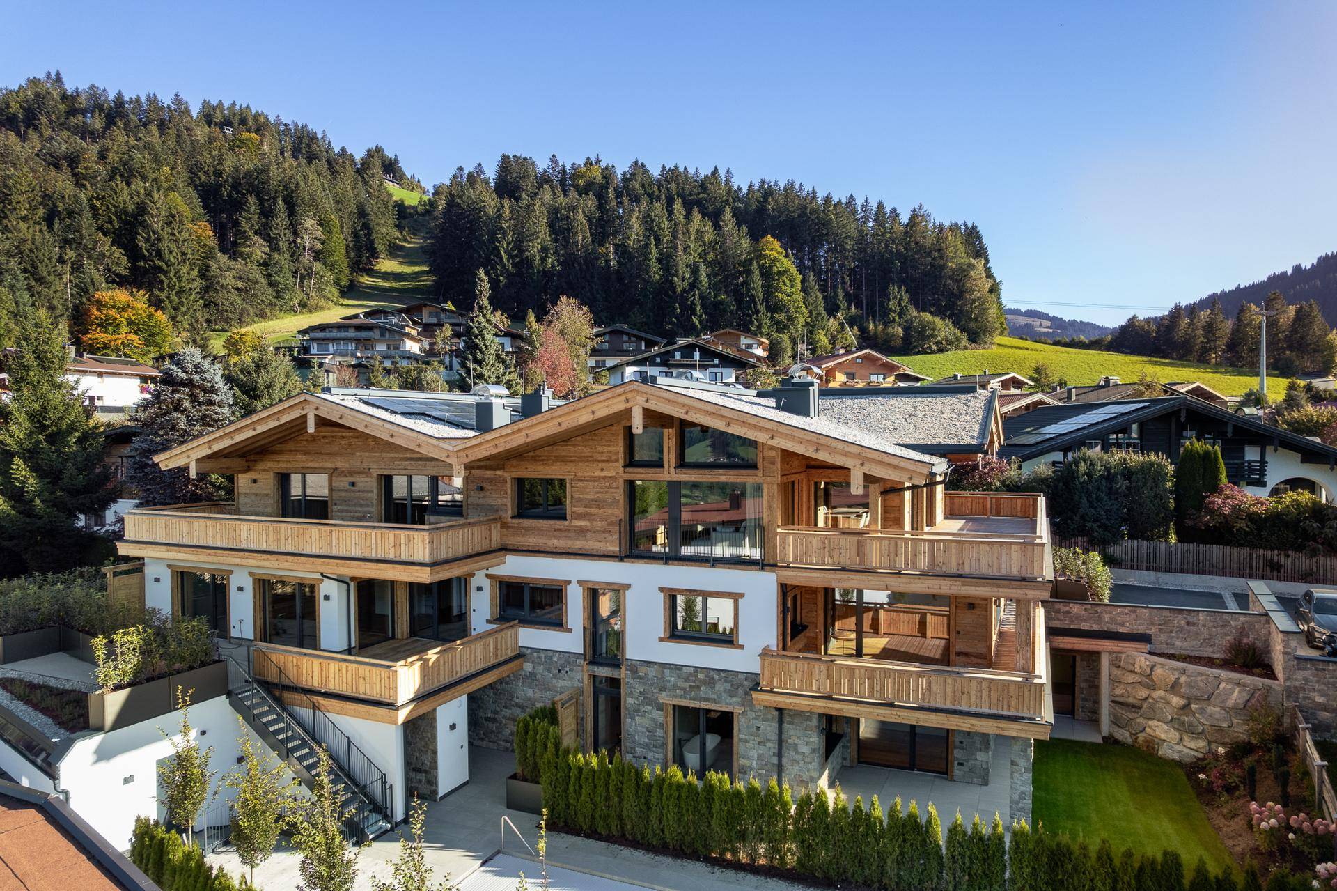 Luxuriöses Chalet in den Alpen mit mehreren Balkonen und Terrassen, umgeben von Natur.