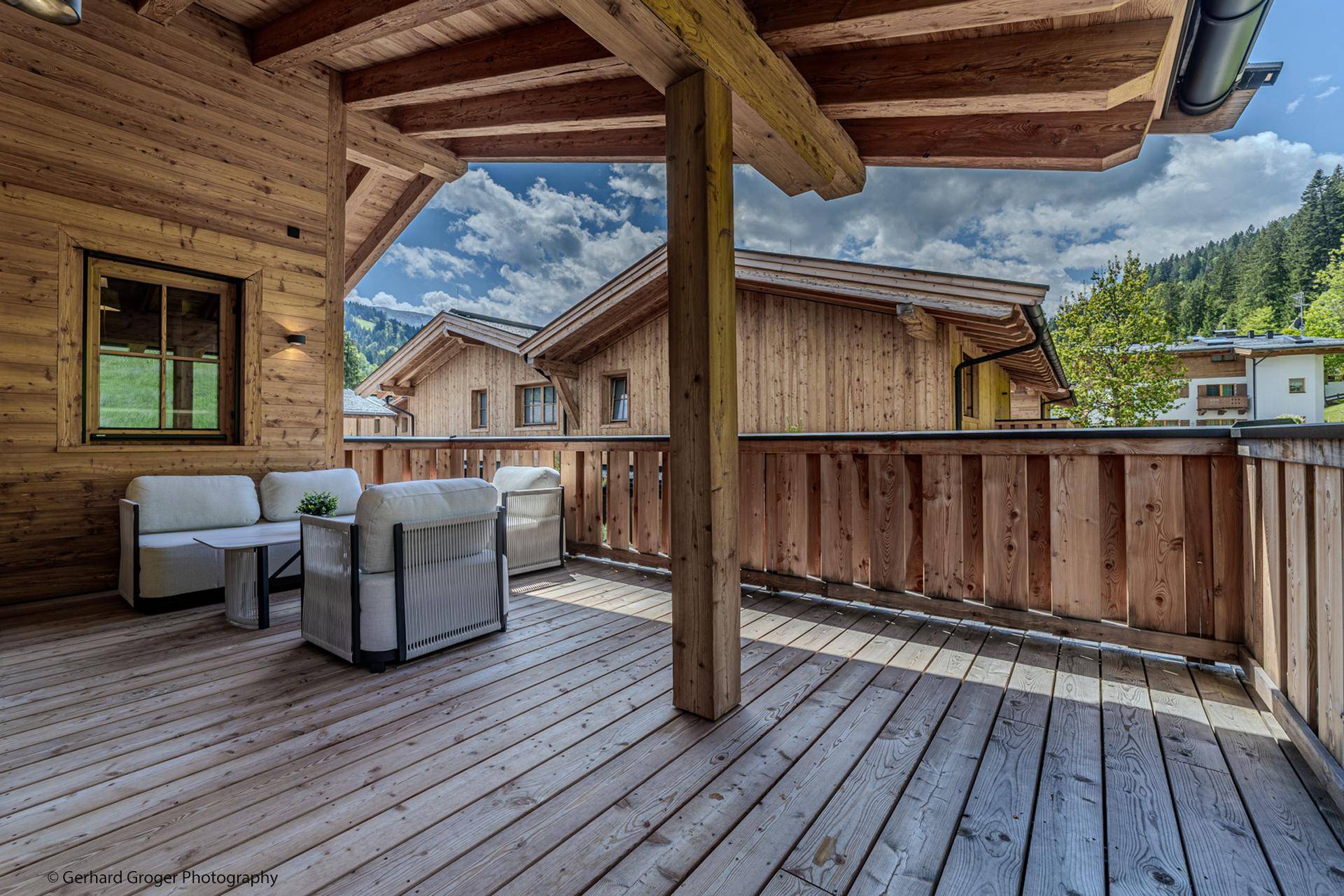 Geräumige Holzterrasse mit Sitzgelegenheiten und Blick auf die umliegende Berglandschaft.