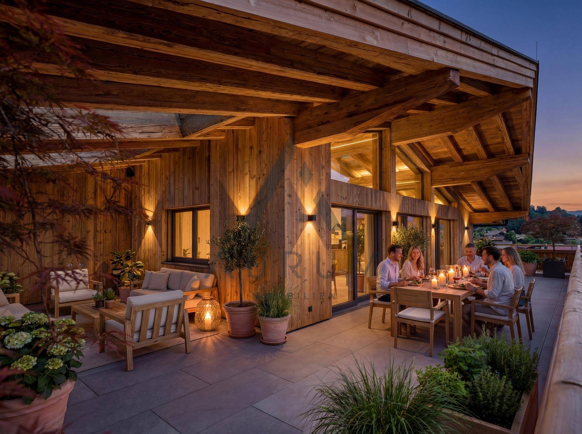 Stimmungsvolle Dachterrasse am Abend mit beleuchteter Holzfassade und geselliger Runde beim Abendessen.