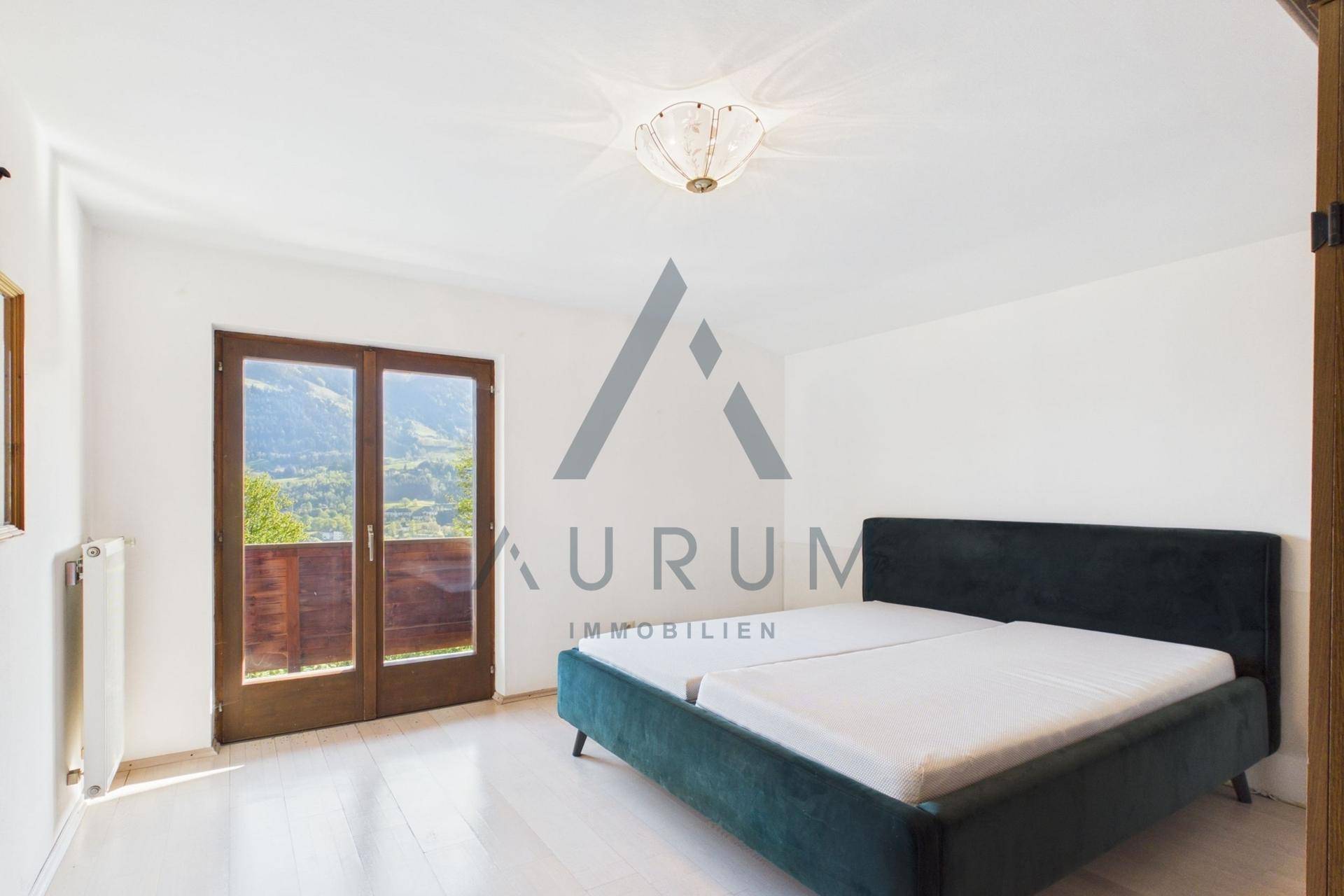 Helles Schlafzimmer mit weißem Holzboden und Zugang zu einem Balkon mit Bergblick.