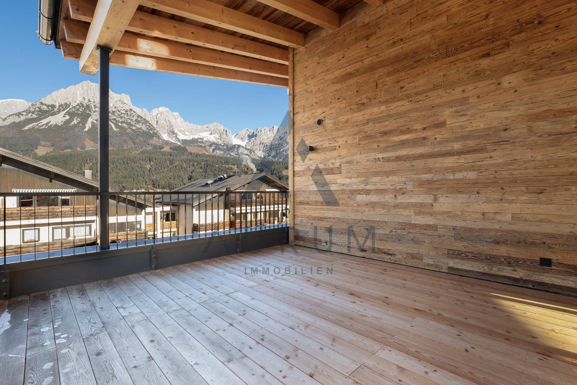 Überdachter Balkon mit Holzboden und atemberaubendem Panoramablick auf die umliegenden Berge.