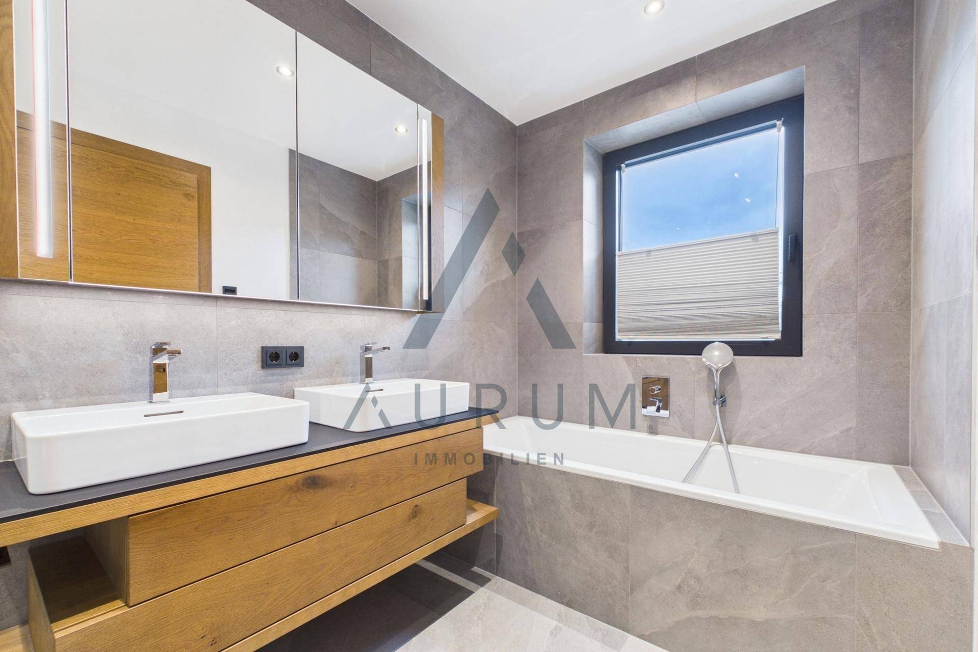Modernes Badezimmer mit Doppelwaschbecken, Badewanne und großem Spiegelschrank, hell gefliest.
