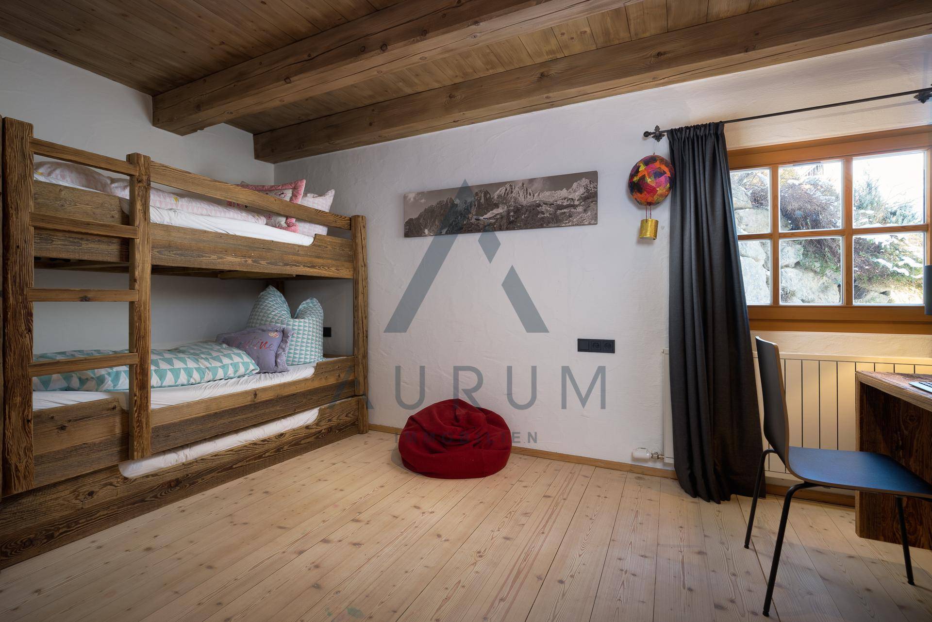 Kinderzimmer mit Etagenbett, Holzboden und einem Fenster mit Blick ins Grüne.