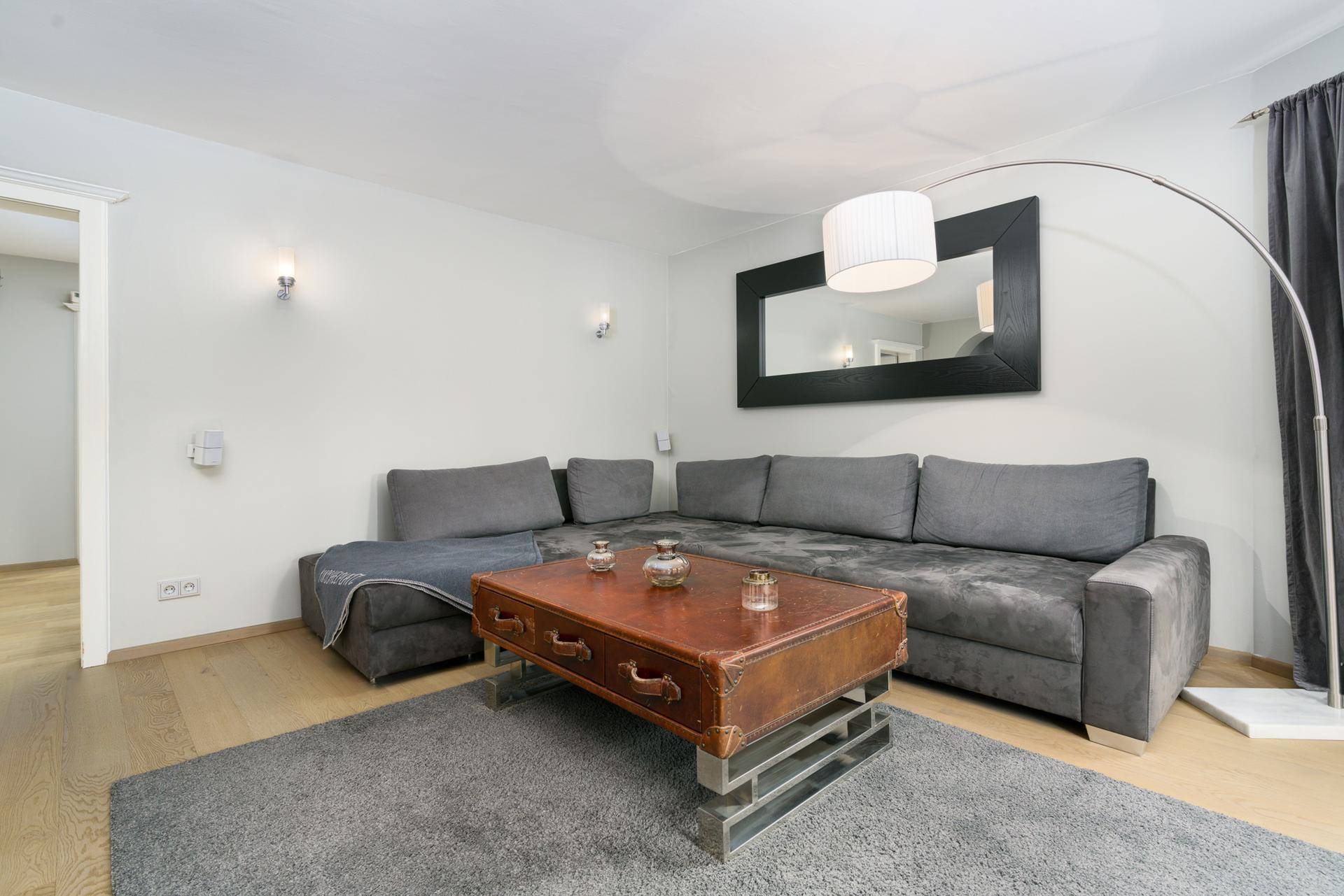 Heller Wohnbereich mit bequemem Ecksofa, stilvollem Couchtisch und großem Spiegel.
