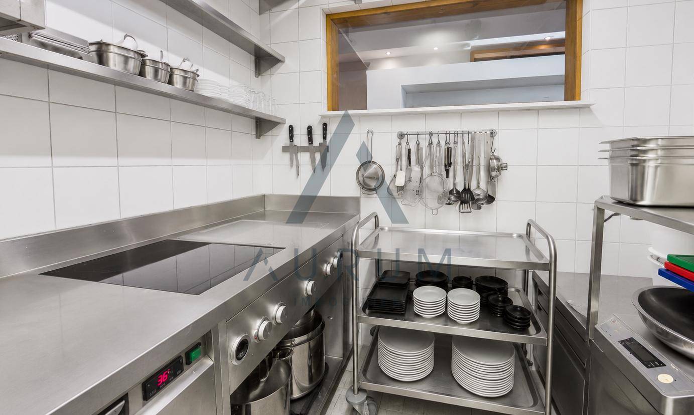 Moderne Gewerbeküche mit Edelstahloberflächen, Induktionskochfeld und weißen Fliesenwänden für professionelles Kochen.
