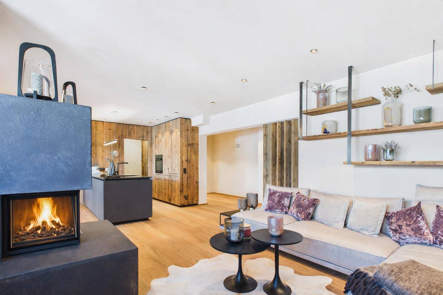 Offener Wohnbereich mit Kamin, Holzwänden und Blick zur modernen Küche.