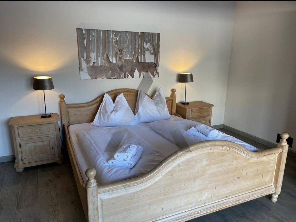 Traditionelles Schlafzimmer mit hellem Holzdoppelbett und rustikalen Nachttischen.