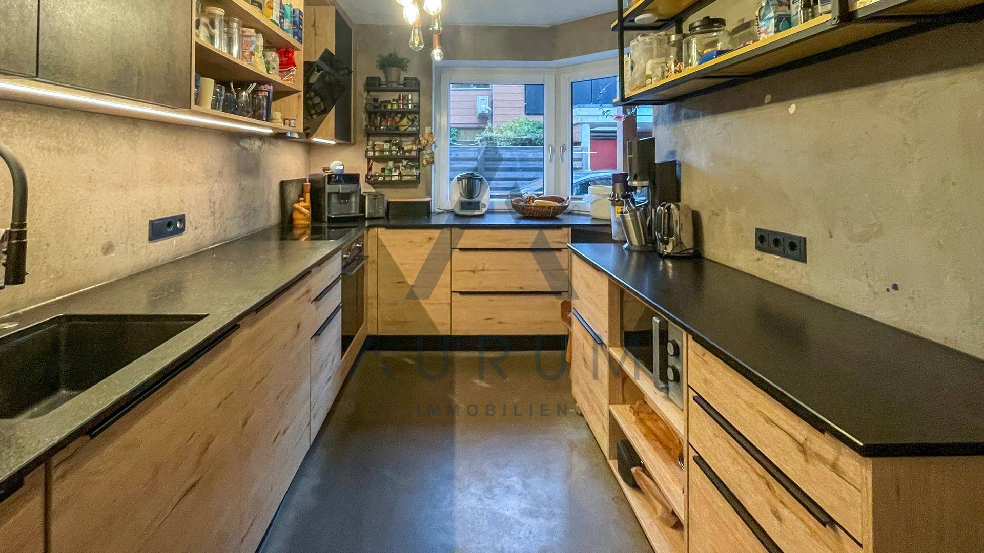 Geräumige Küche mit viel Stauraum, modernen Holzschränken und dunklen Arbeitsflächen.