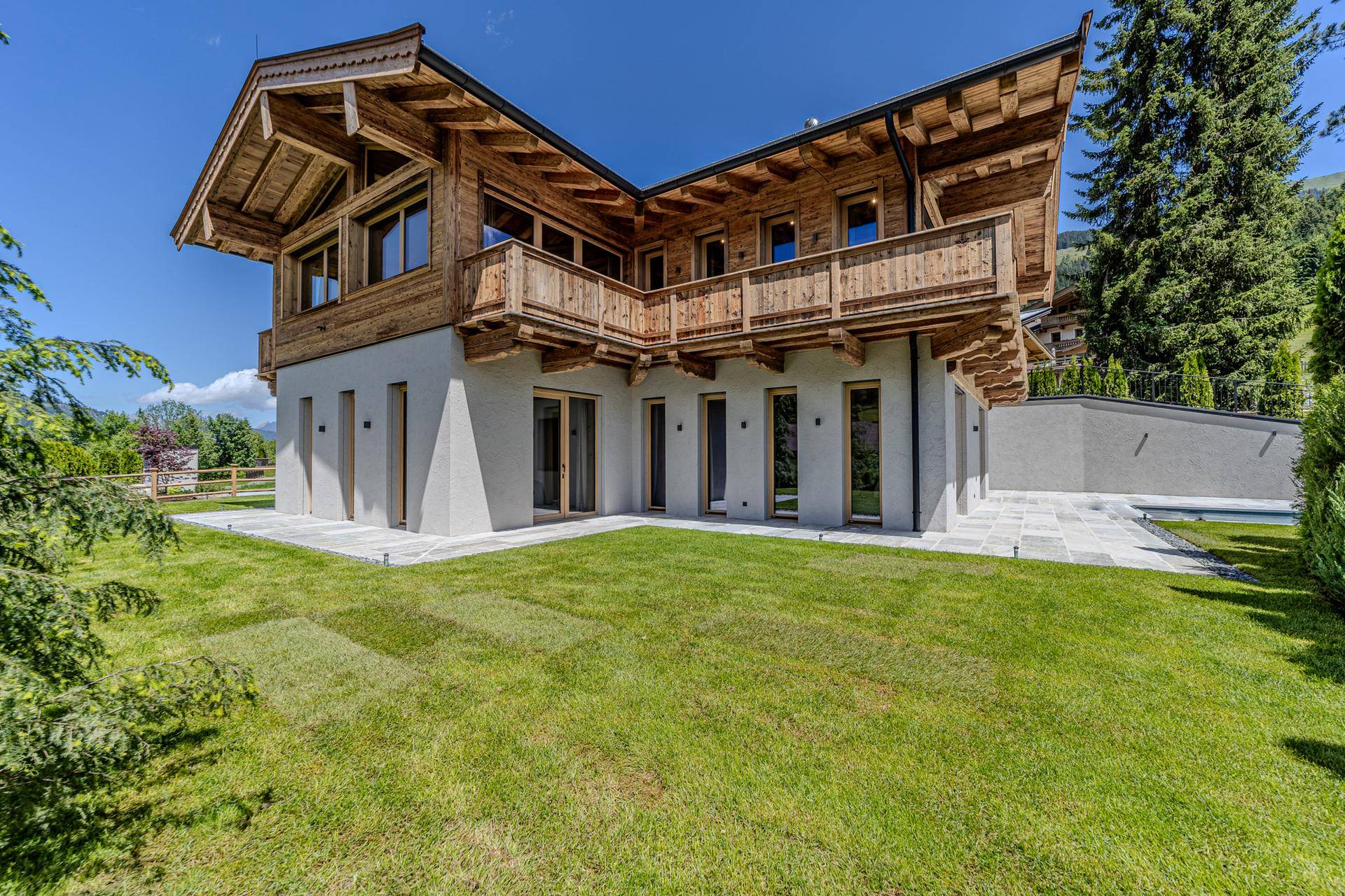 Moderne Chalet-Villa bei Tag mit gepflegtem Rasen und weitläufigem Gartenbereich.
