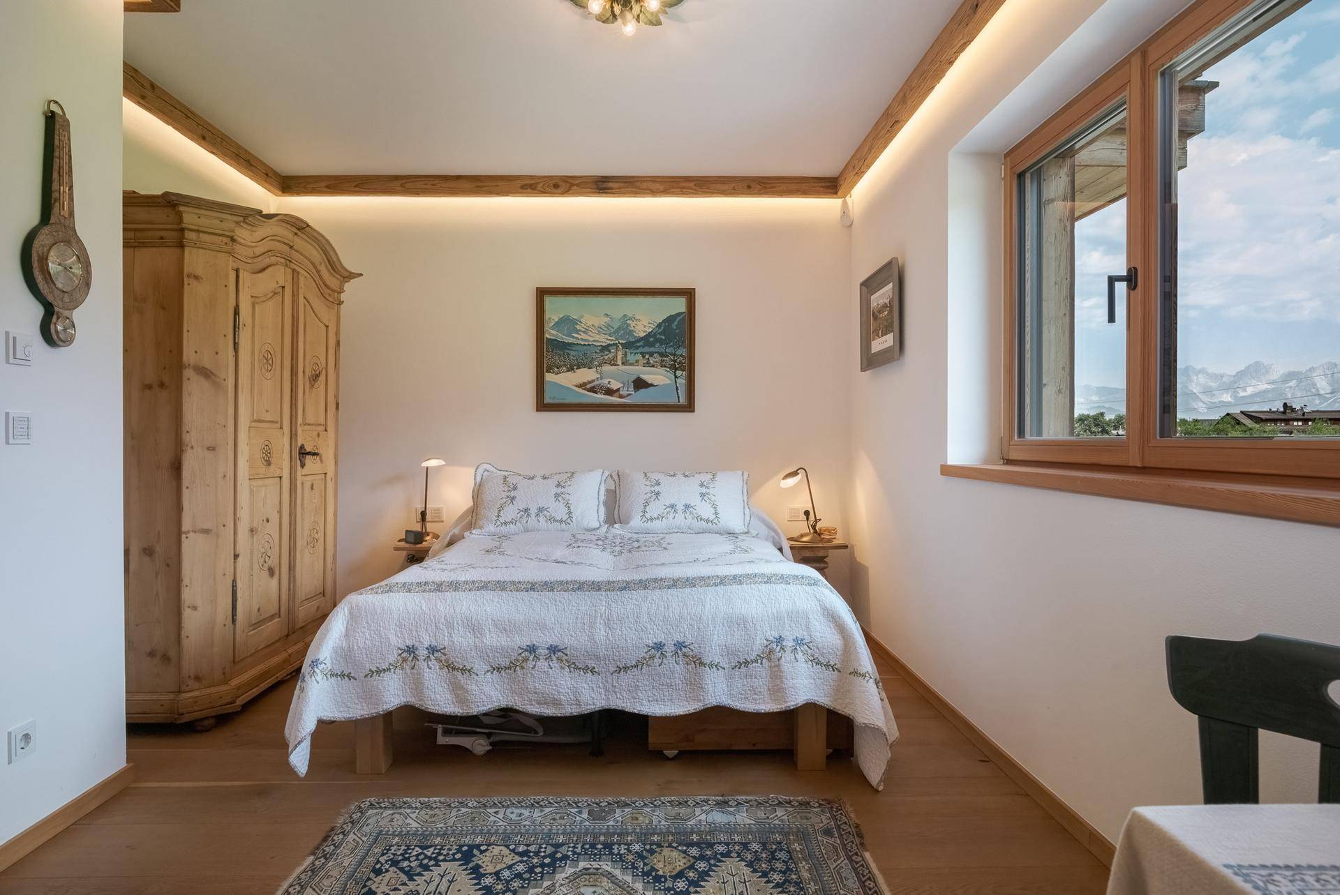 Gemütliches Schlafzimmer mit Holzbett, traditionellem Schrank und weitem Bergblick.