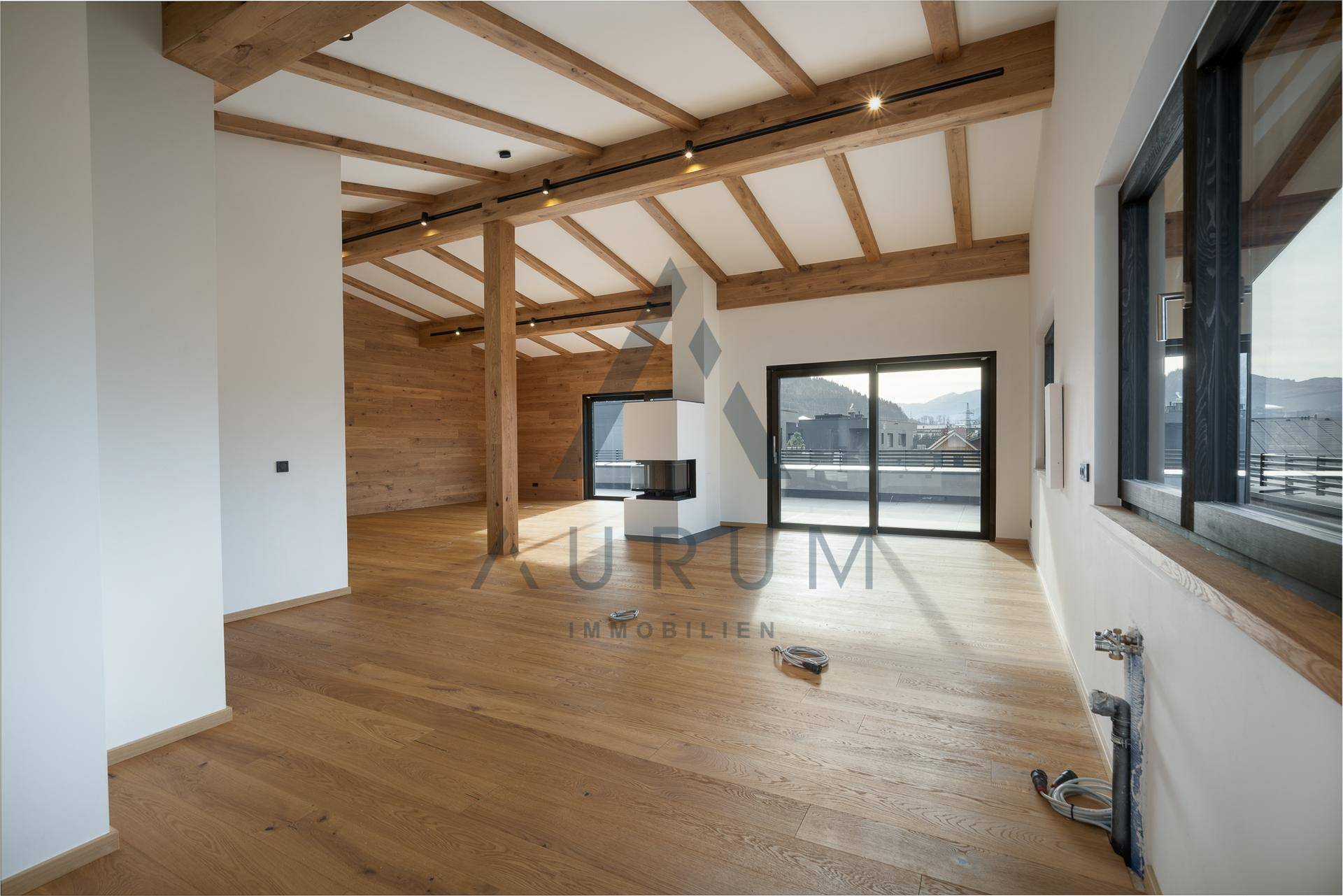 Lichtdurchfluteter Wohnbereich mit Holzwänden, sichtbaren Balken und großzügigen Fensterfronten.