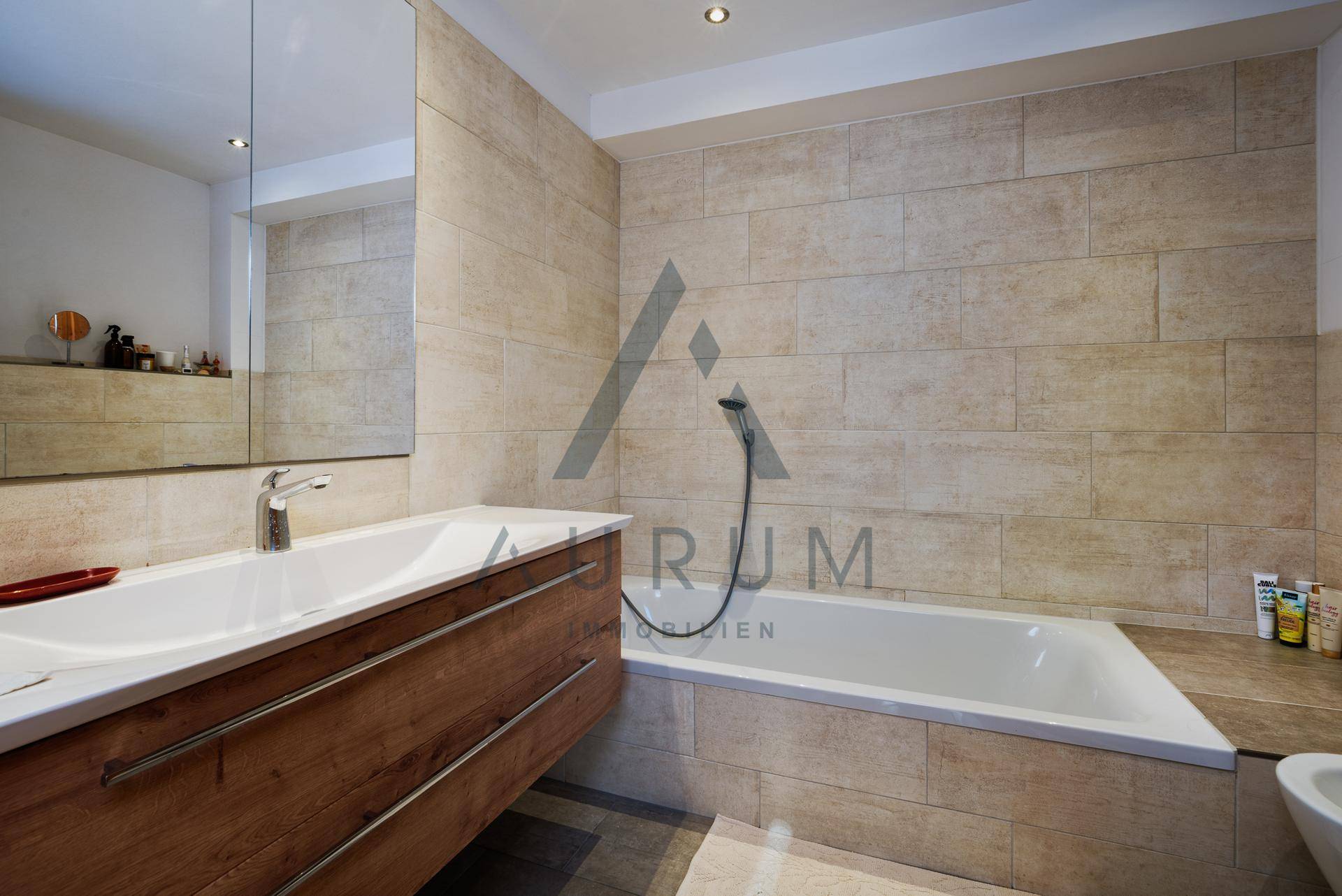 Modernes Badezimmer mit Badewanne, Einzelwaschbecken und hellen Fliesen an den Wänden.